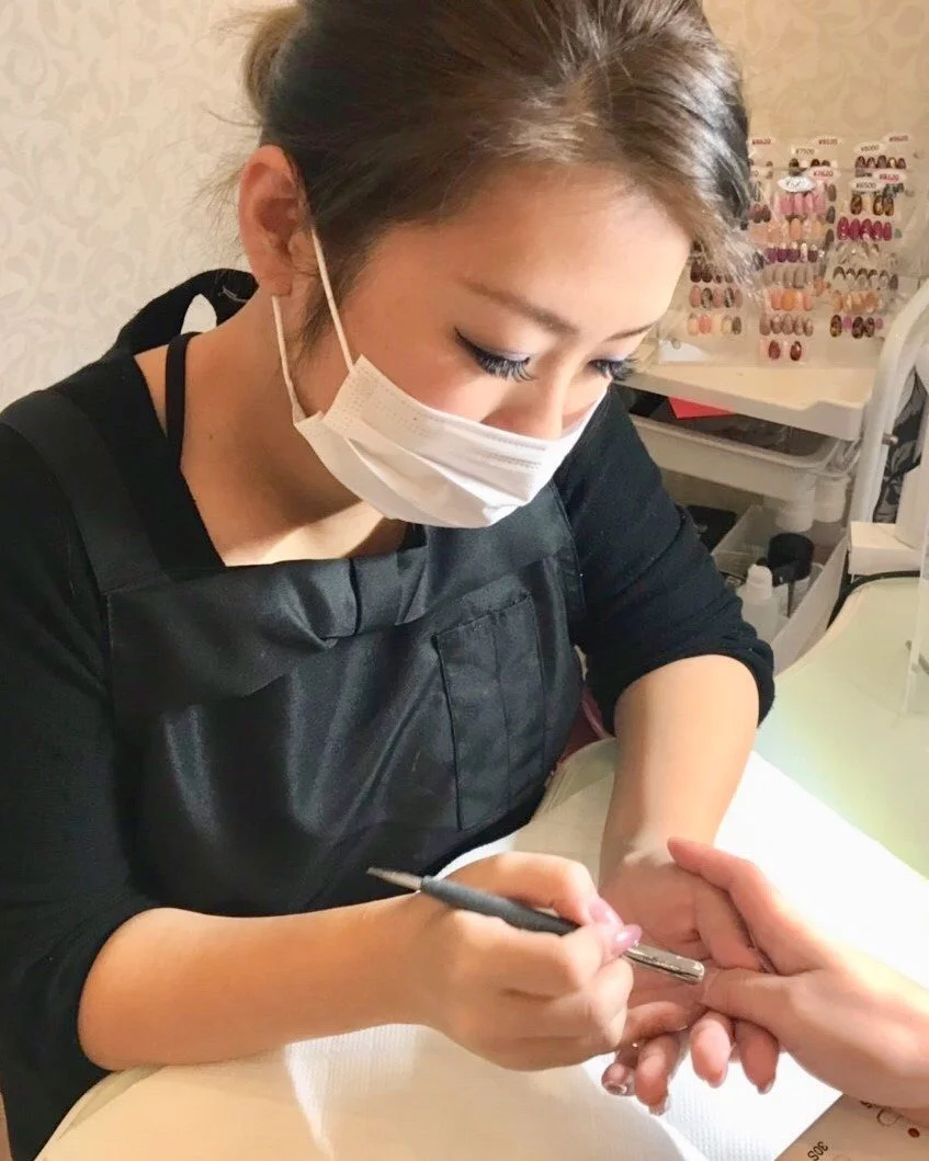 ネイルアーティストが手にネイルアートを施している様子