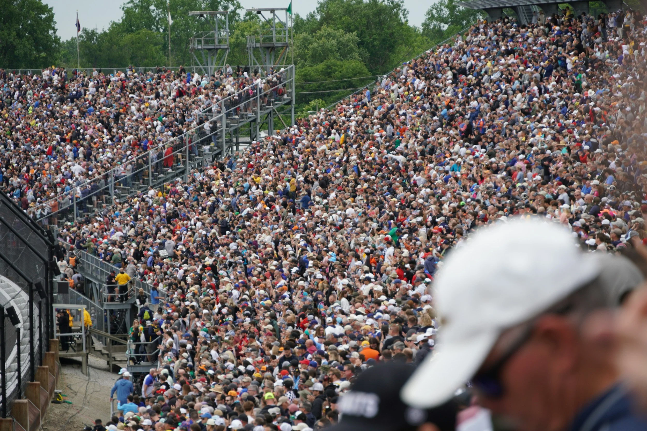 A large crowd of people seated in bleachers at an outdoor stadium.