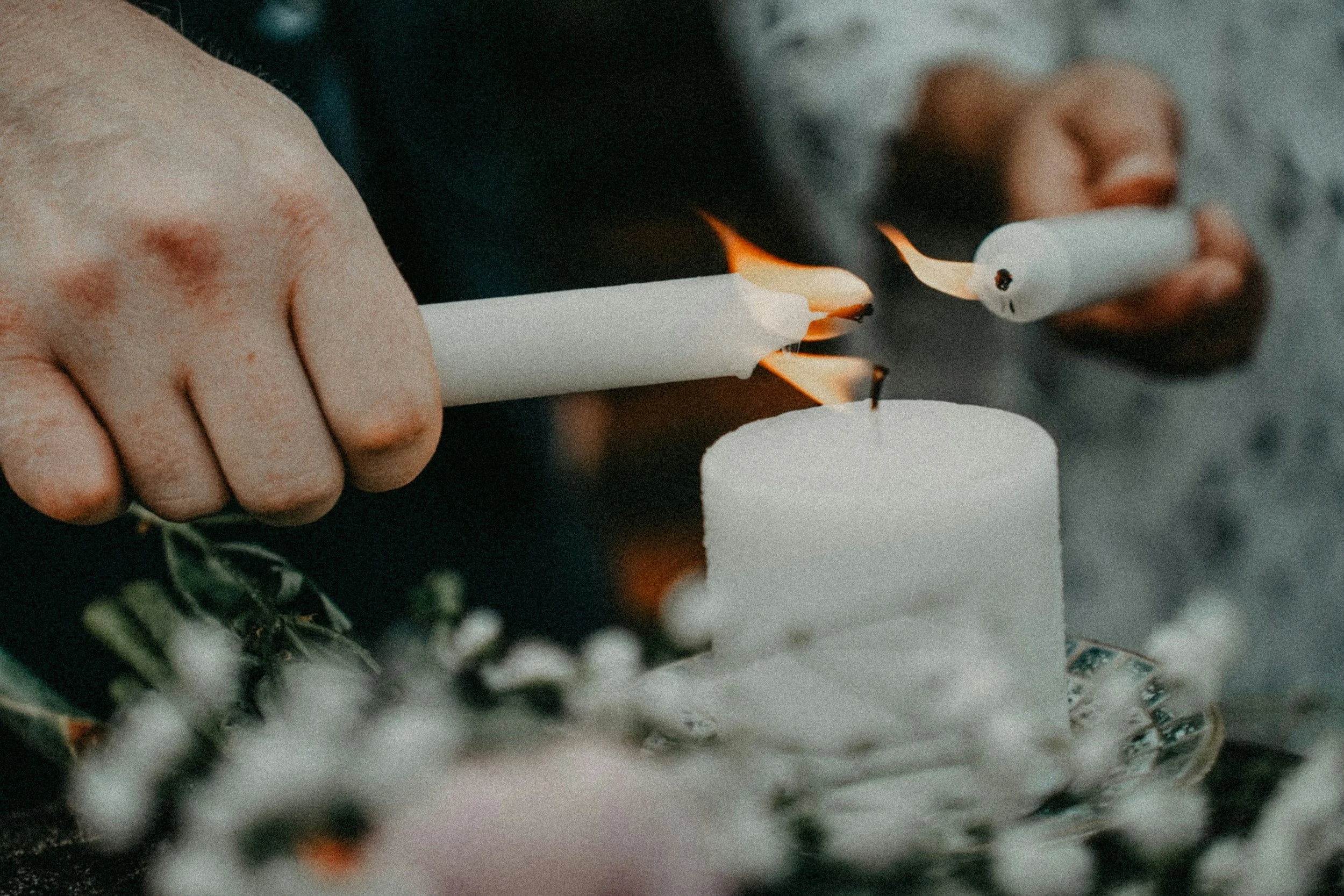 Person lighting a white candle with a match