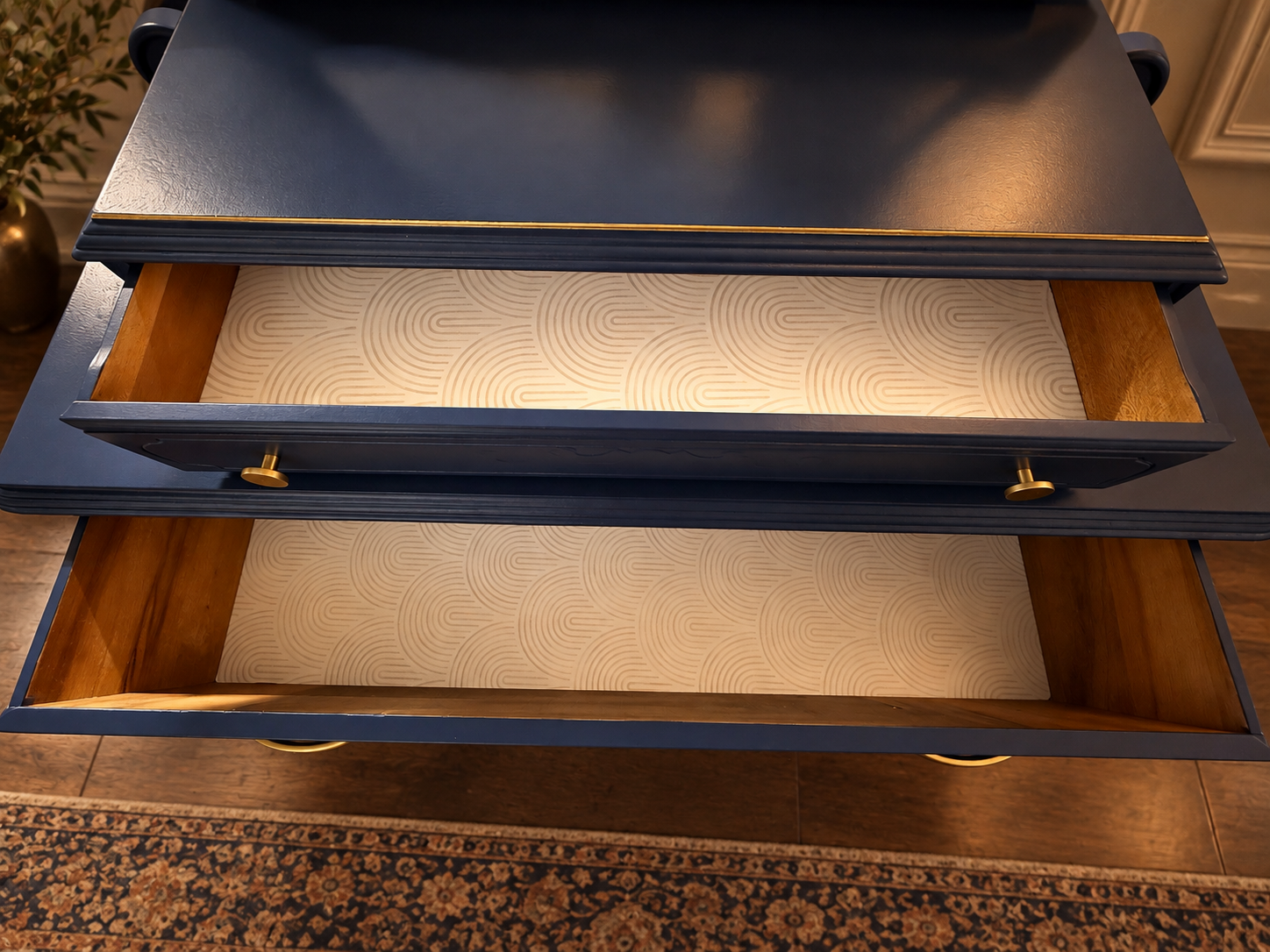 Open drawers of The Lune Noire Vanity revealing natural wood interiors and ivory geometric-patterned drawer liners beneath the deep navy exterior.