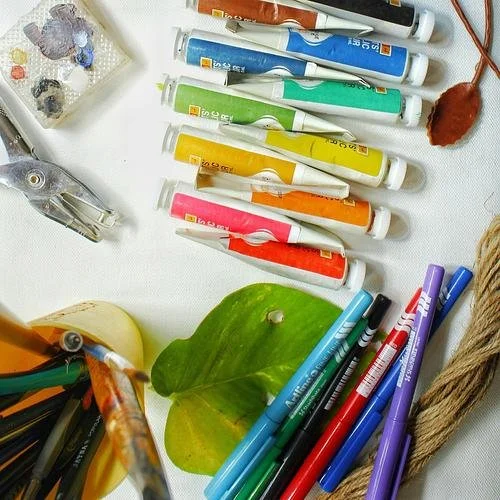 A flat lay of colorful art supplies, including paint tubes and markers, used for creative connection and tactile activities at The Landline.