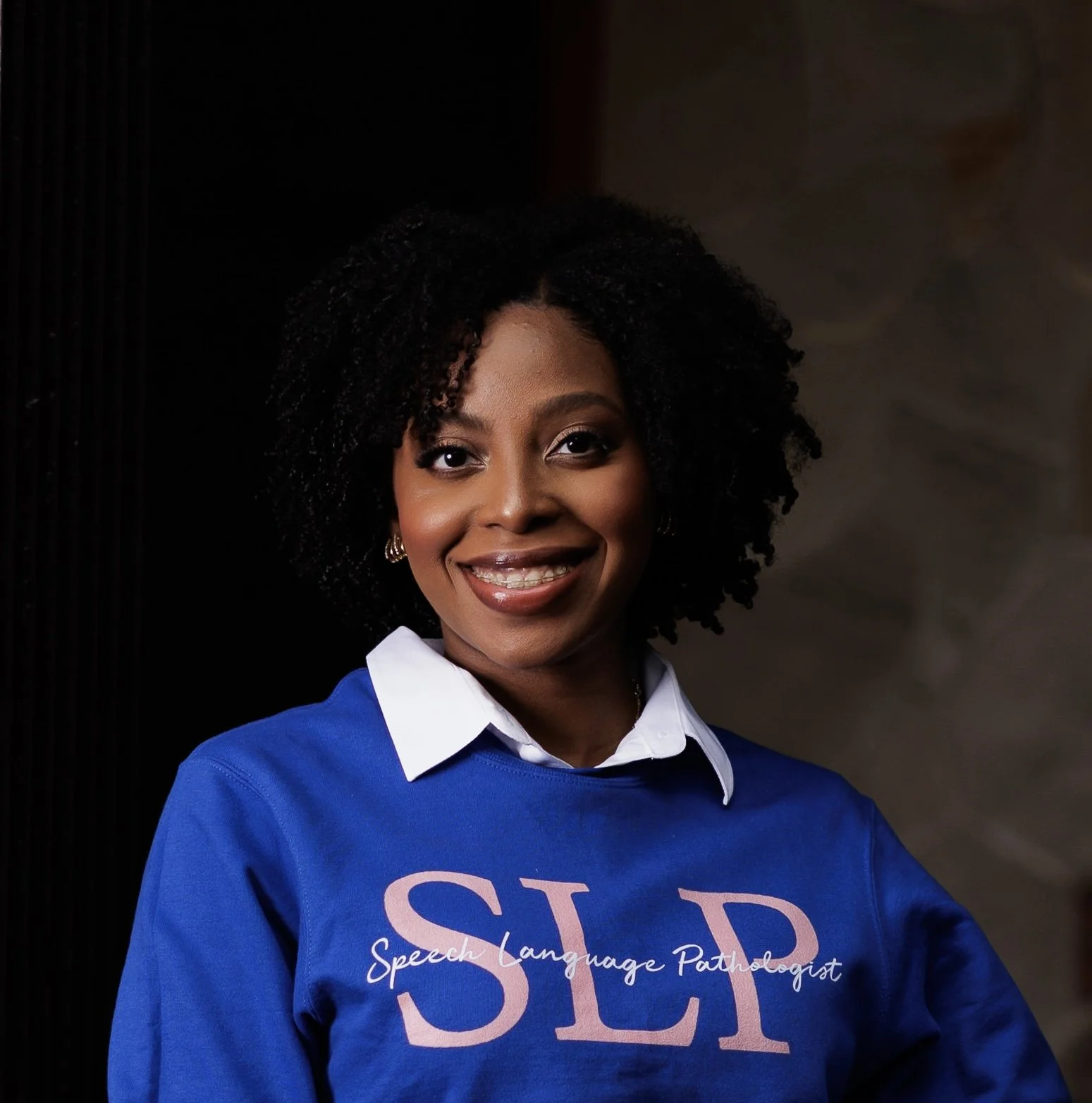 Speech-language pathologist smiling in a blue Speech Language Pathologist sweatshirt.