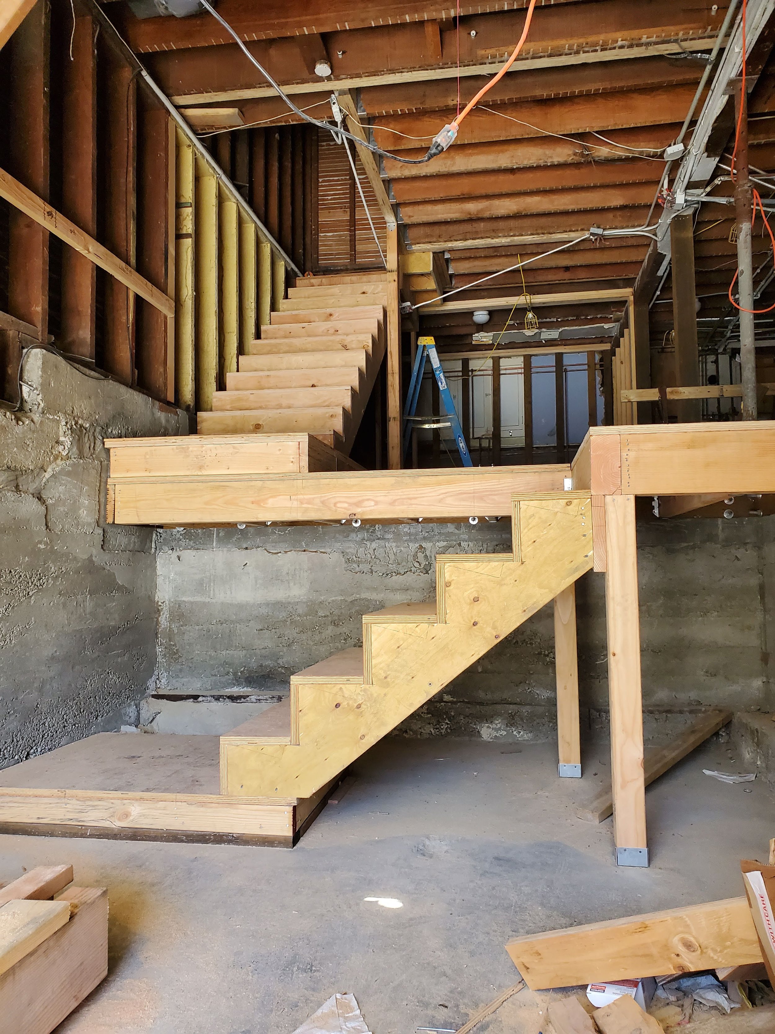 Construction site showing newly built wooden stairs and framing inside a building under renovation.