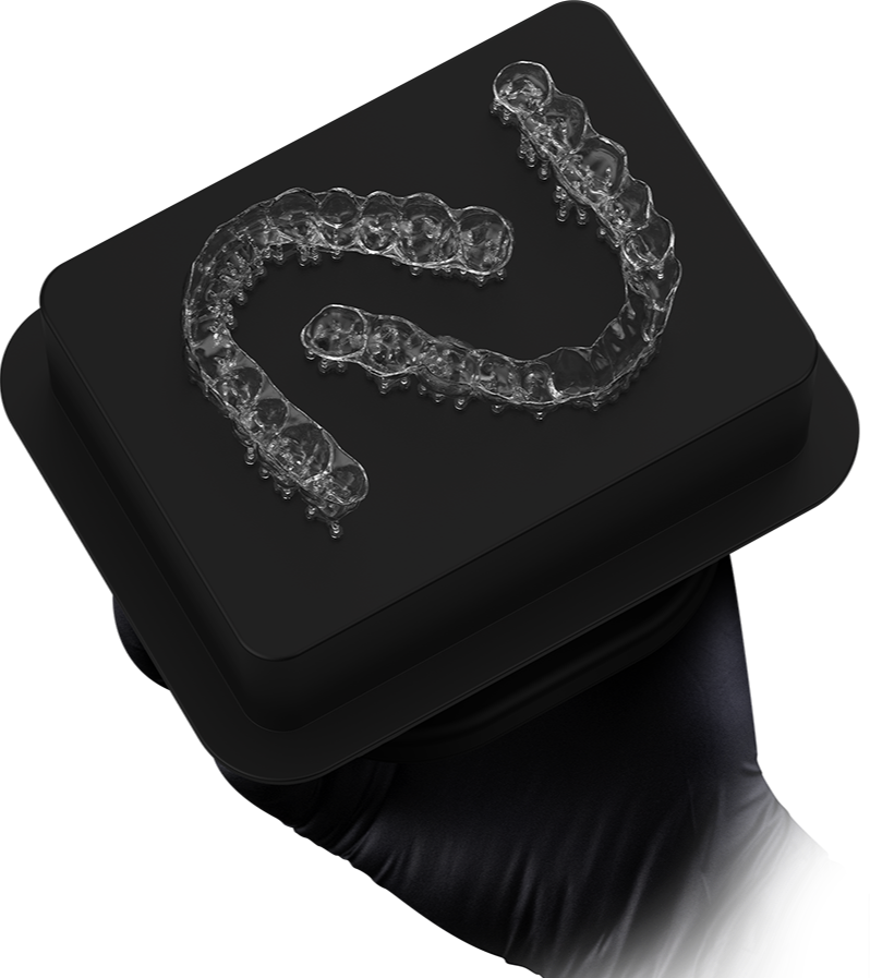 A black handheld device with a clear dental aligner on top.