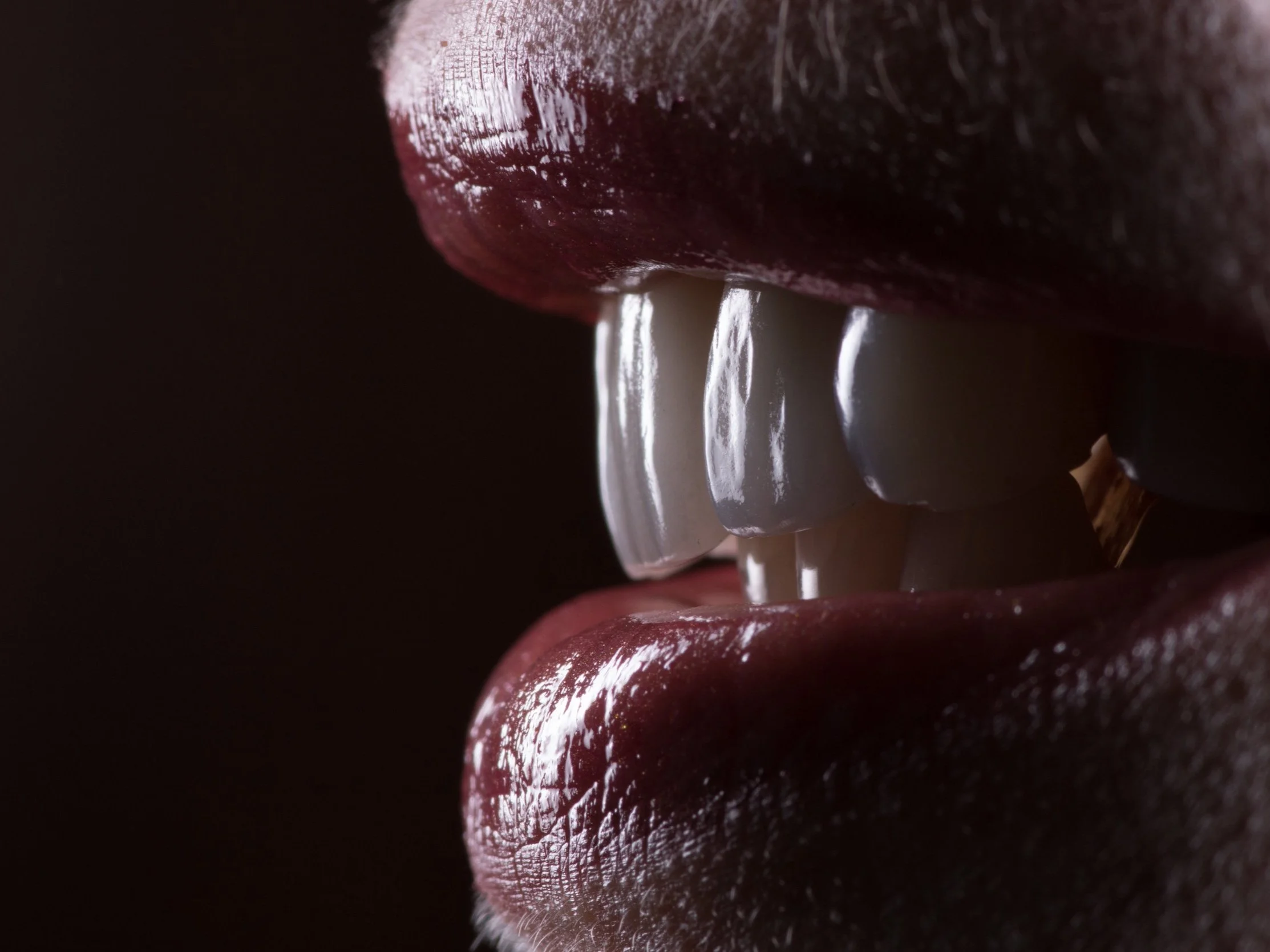 Close-up of lips with white teeth visible, lips are slightly parted.