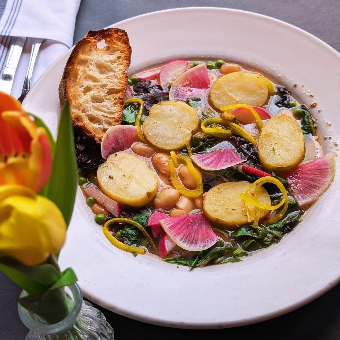 Spring Butter Bean Stew &bull; lemony herb broth, swiss chard, yukon gold potato, watermelon radish, english peas, pickled onions, toasted ciabatta (vegan and GFA 😚)