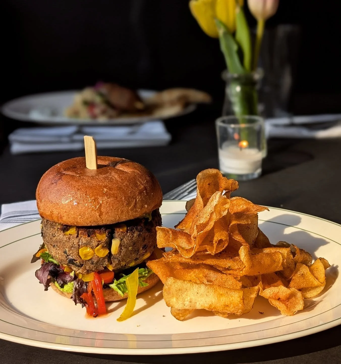 Vegan Southwest Black Bean Burger with roasted red pepper, corn, avocado almond "crema," pickled onions, house kettle chips 🌱