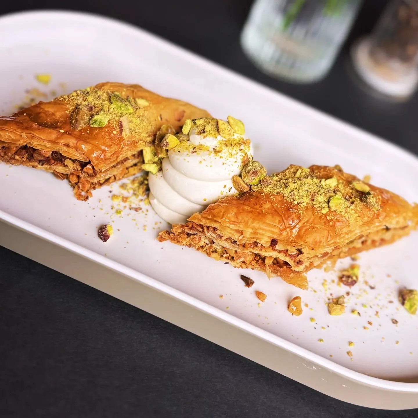 Flaky and flavorful Baklava with crushed pistachios, honey, and fresh whipped cream ☀️