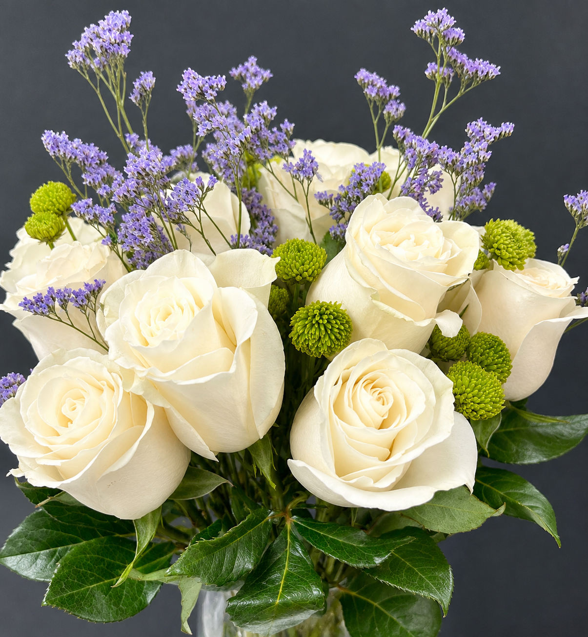 Custom floral arrangement featuring white roses, lavender flowers, green chrysanthemums, and soft blue-green eucalyptus.