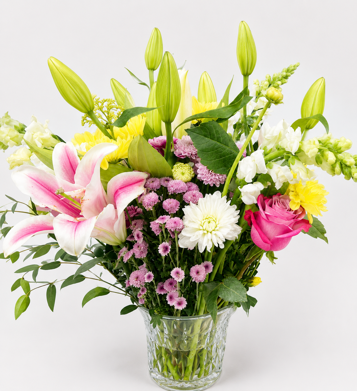 Colorful custom floral arrangement featuring pink roses, lilies, green chrysanthemums, and seasonal flowers and greenery.