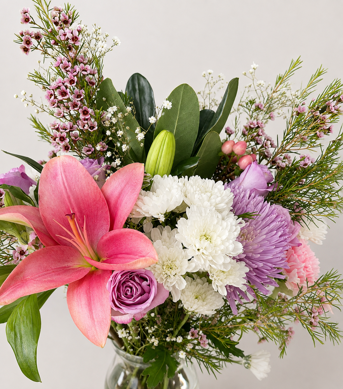 Custom floral arrangement featuring pink lilies, white chrysanthemums, lavender flowers, and delicate seasonal greenery.