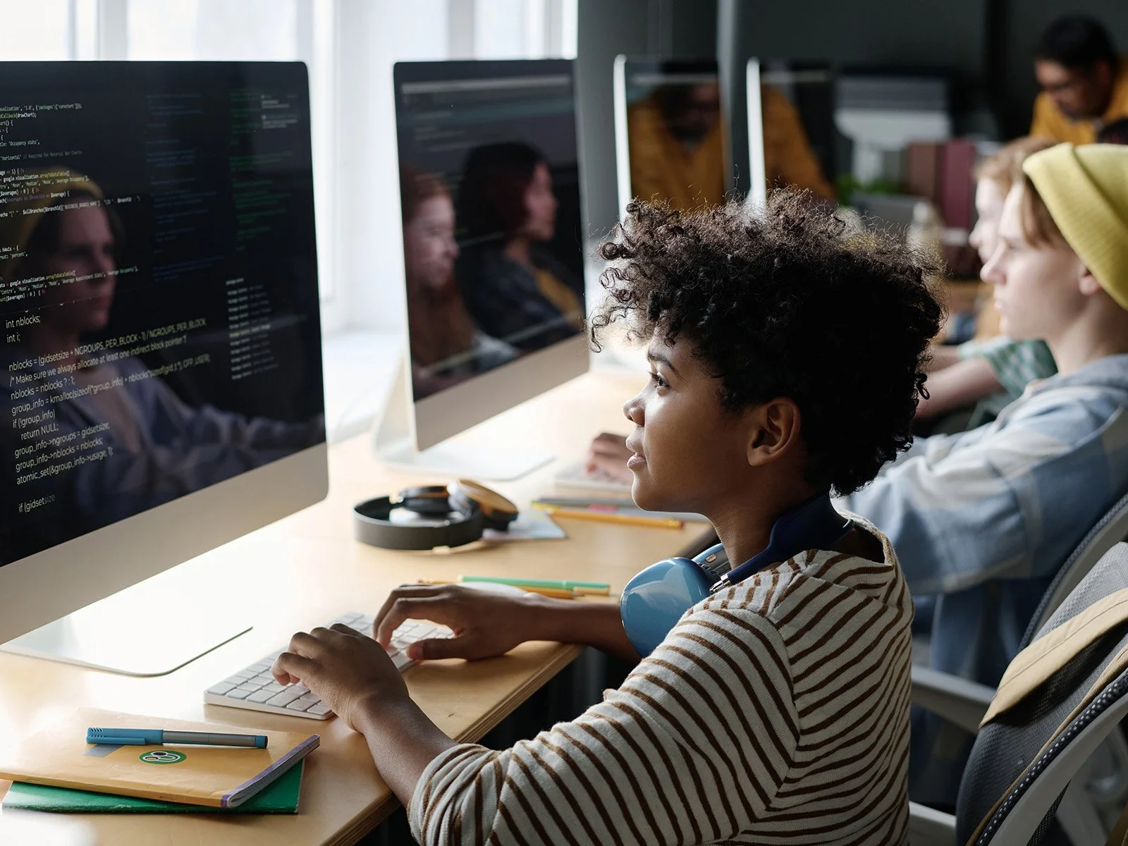 Student writing code on a desktop computer during a creative technology class.