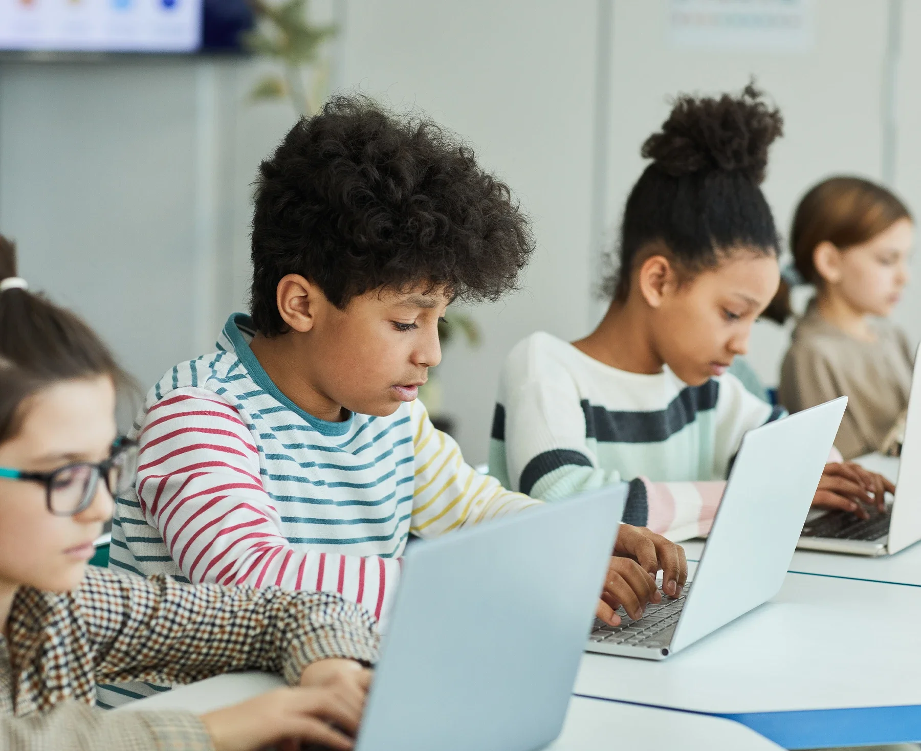 Middle and high school students collaborating on laptops during a summer game development program