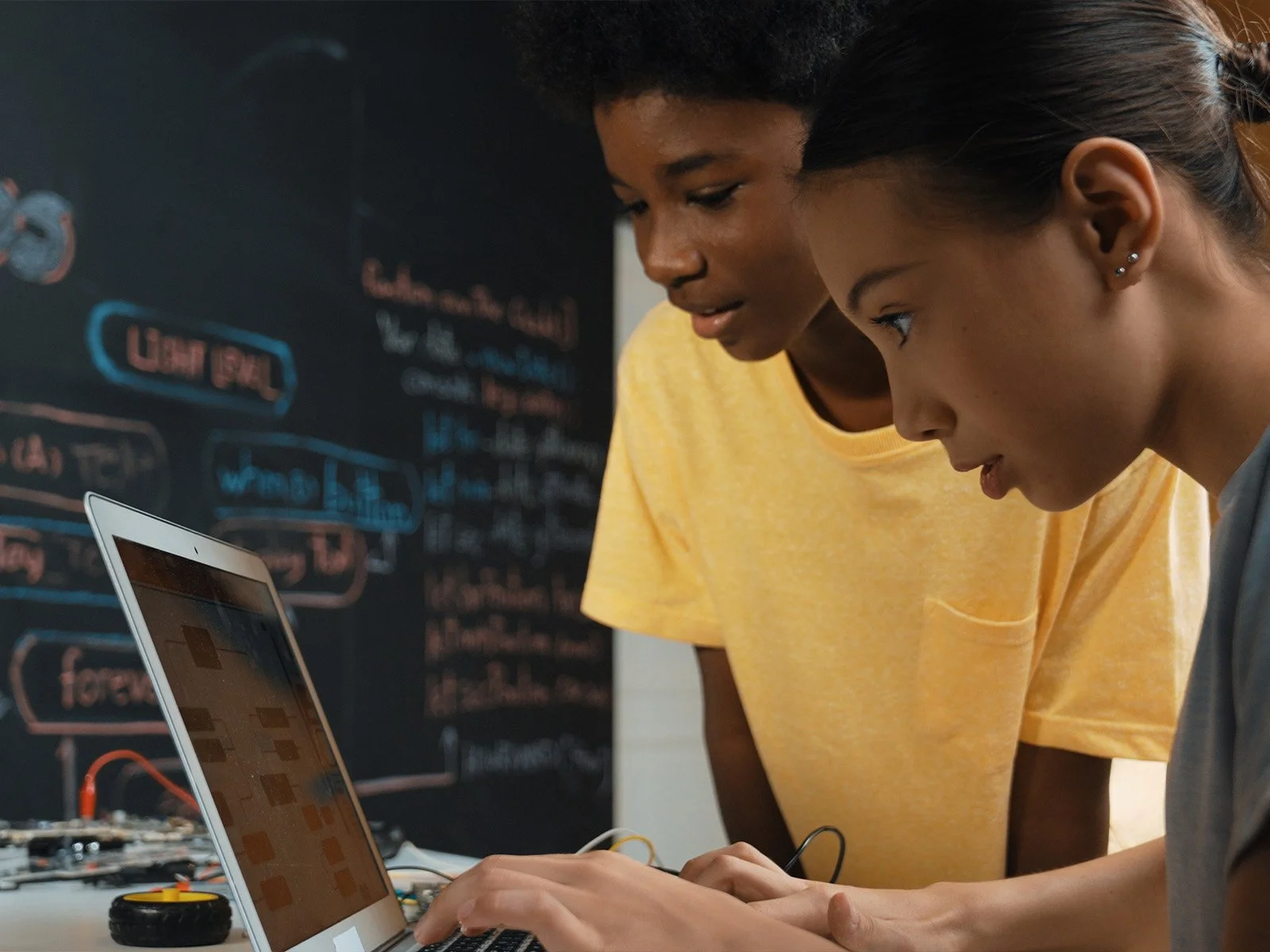 Two students collaborating on a laptop while developing a digital project.