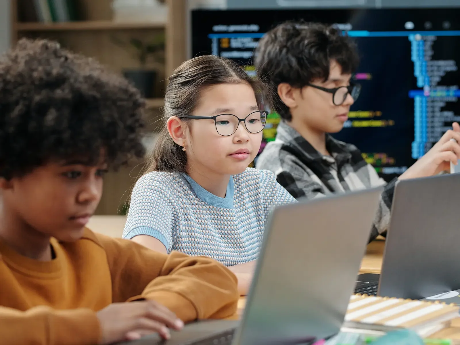 Middle school students learning programming and technology skills on laptops in a classroom