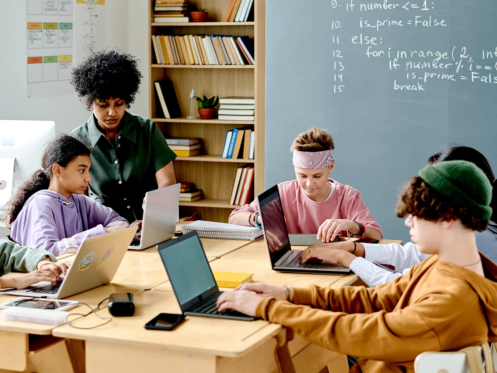 Students learning game development together in a classroom using laptops with teacher guidance