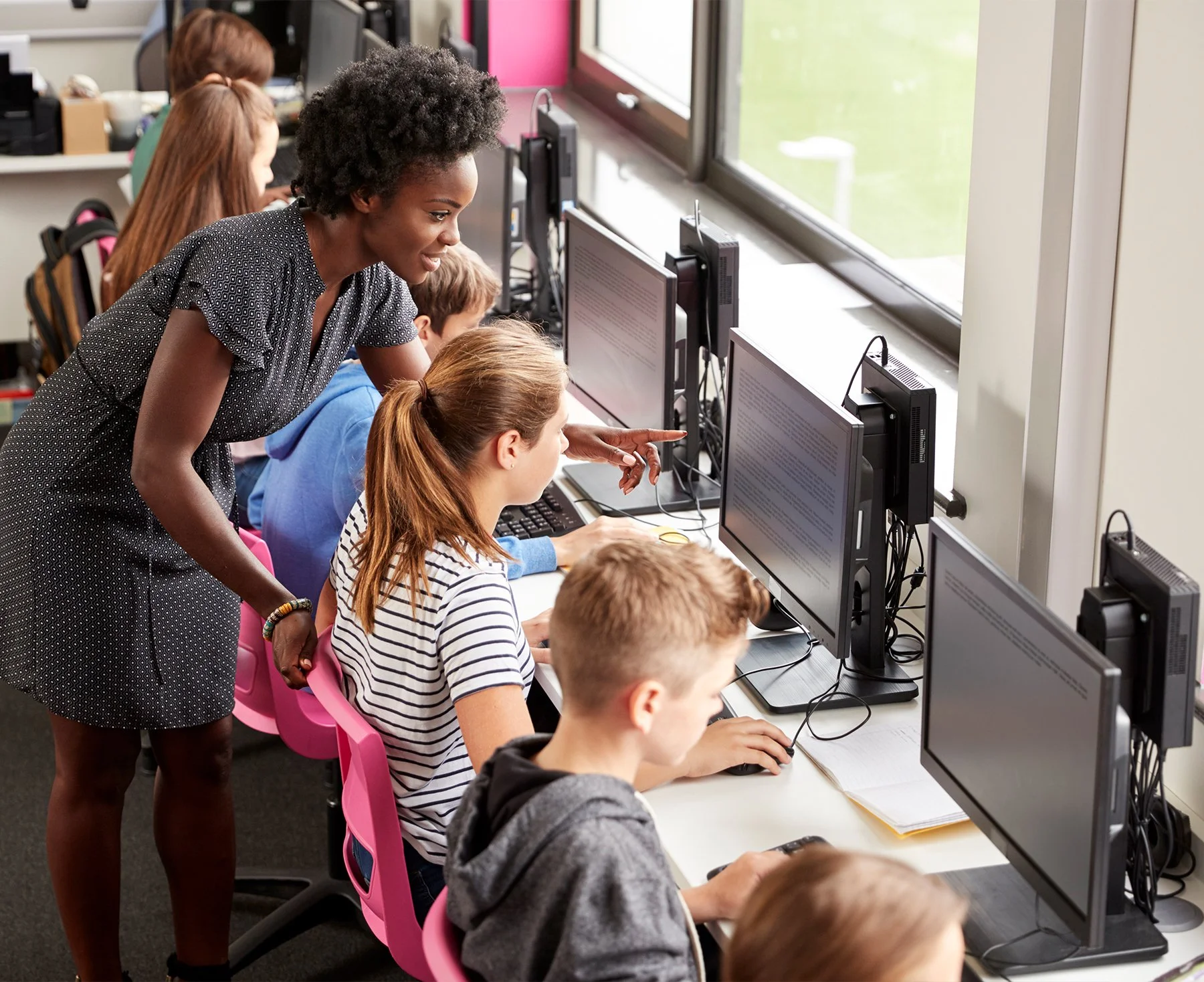 After-school game development students receive mentor guidance in a computer lab classroom.