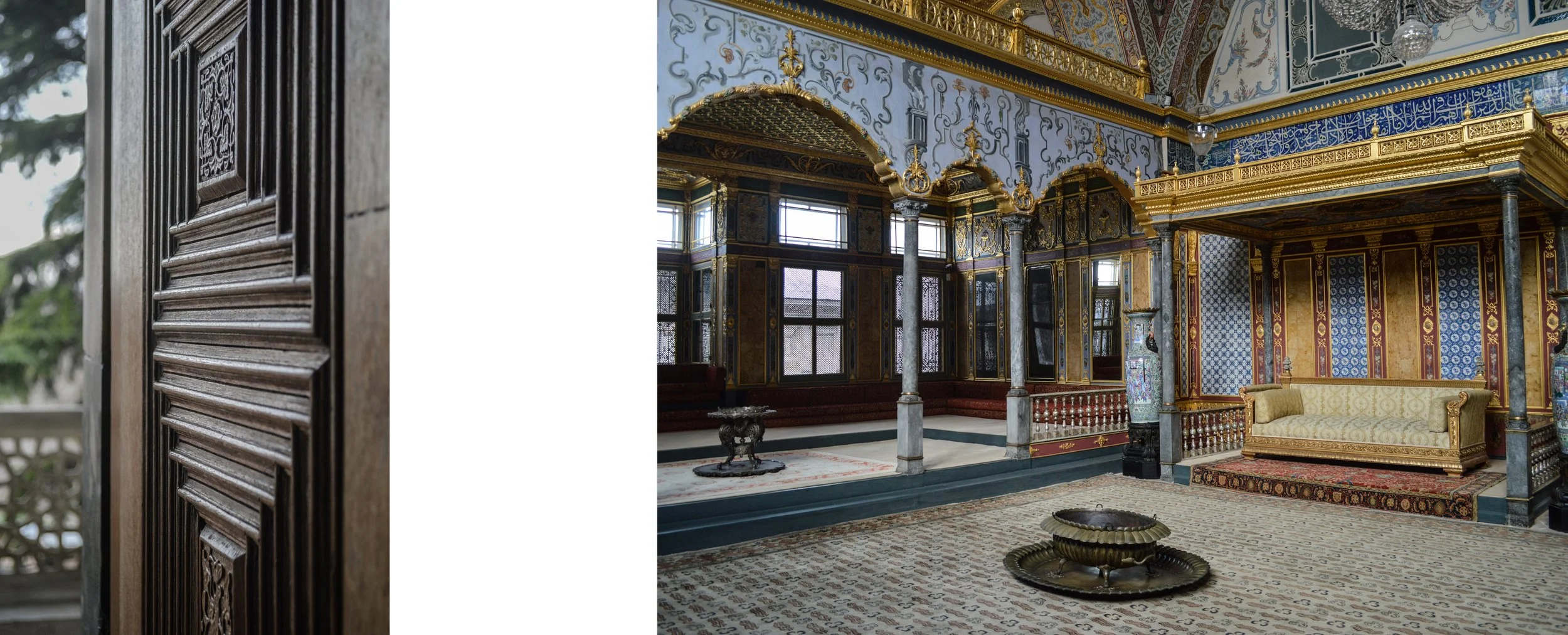 Interior of a decorated room with ornate walls, columns, large windows, and a gold and blue color scheme, featuring a cushioned sofa and patterned carpet.