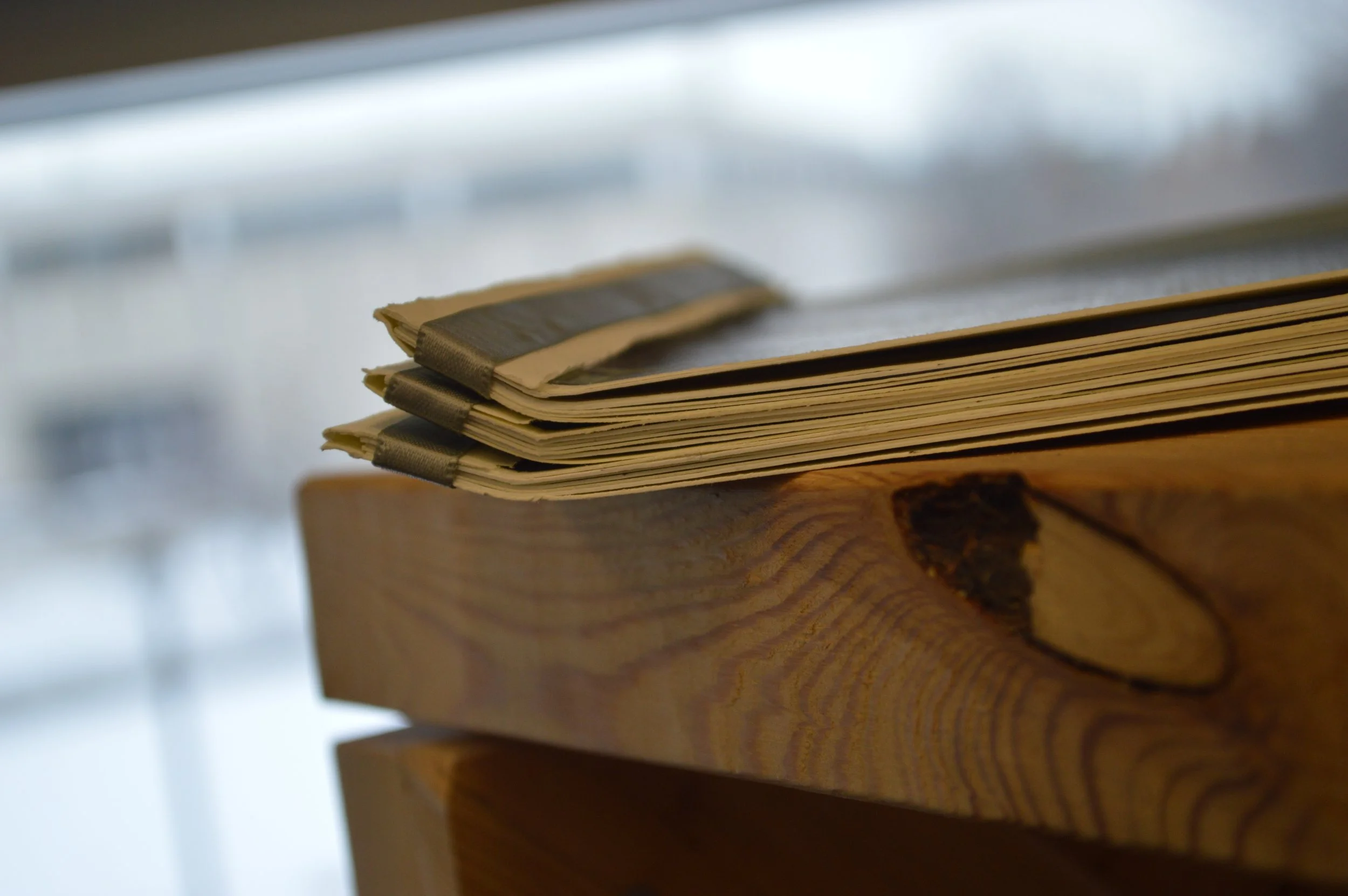 Stack of old papers bound with black tape, resting on a wooden surface.