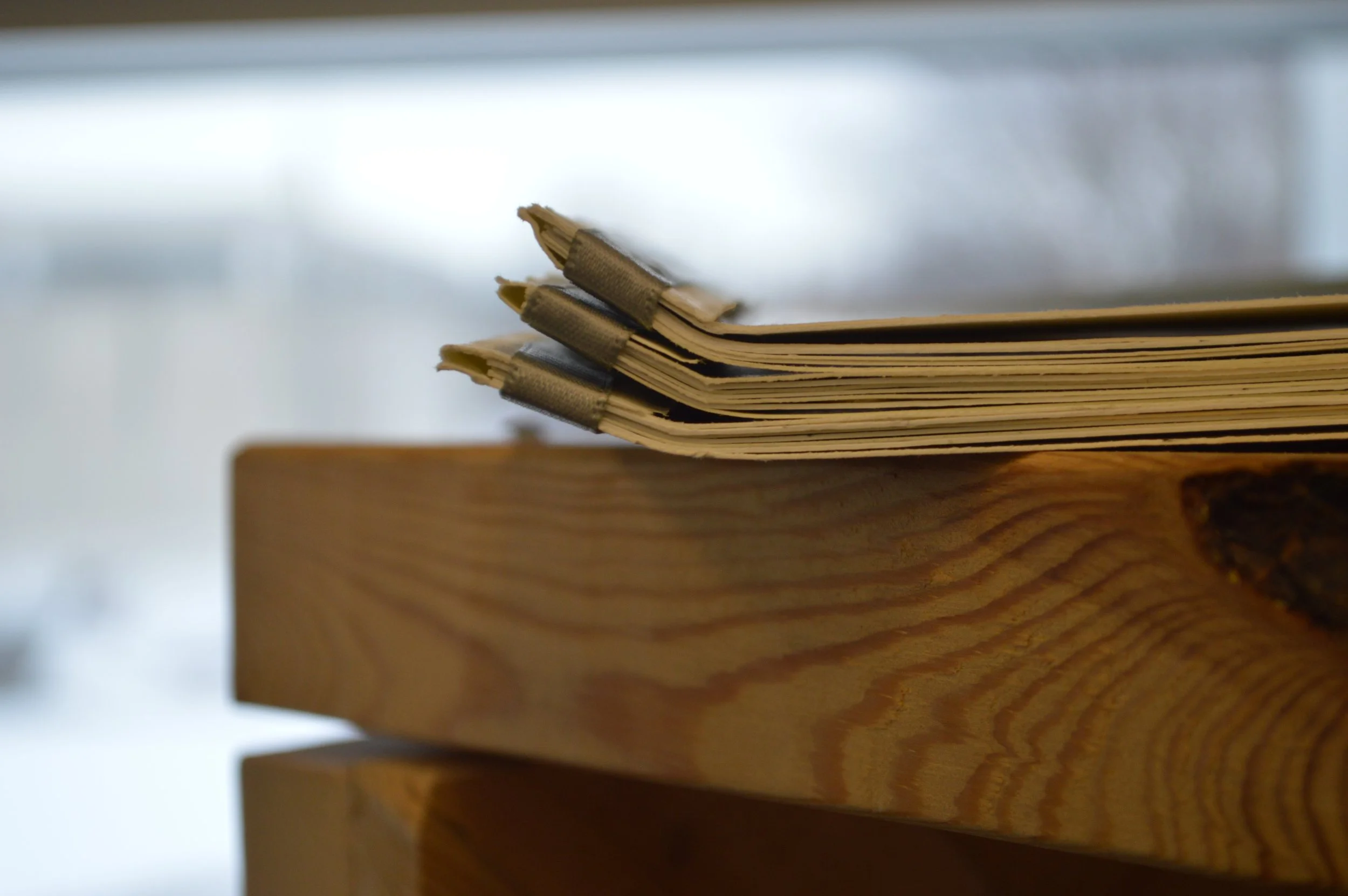 Close-up of a stack of cardboard or paper folders with elastic bands on a wooden surface.