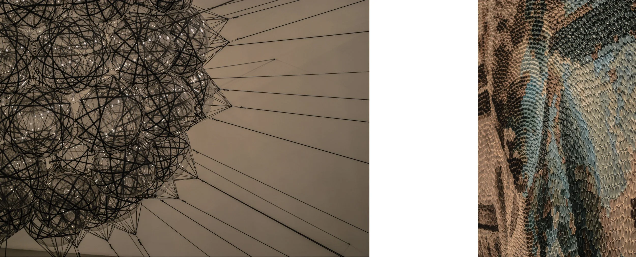 Close-up of a modern chandelier made of numerous glass spheres and black metal wire frames with long suspension wires, and an abstract textured piece with tightly packed blue, black, and beige scales or feathers.