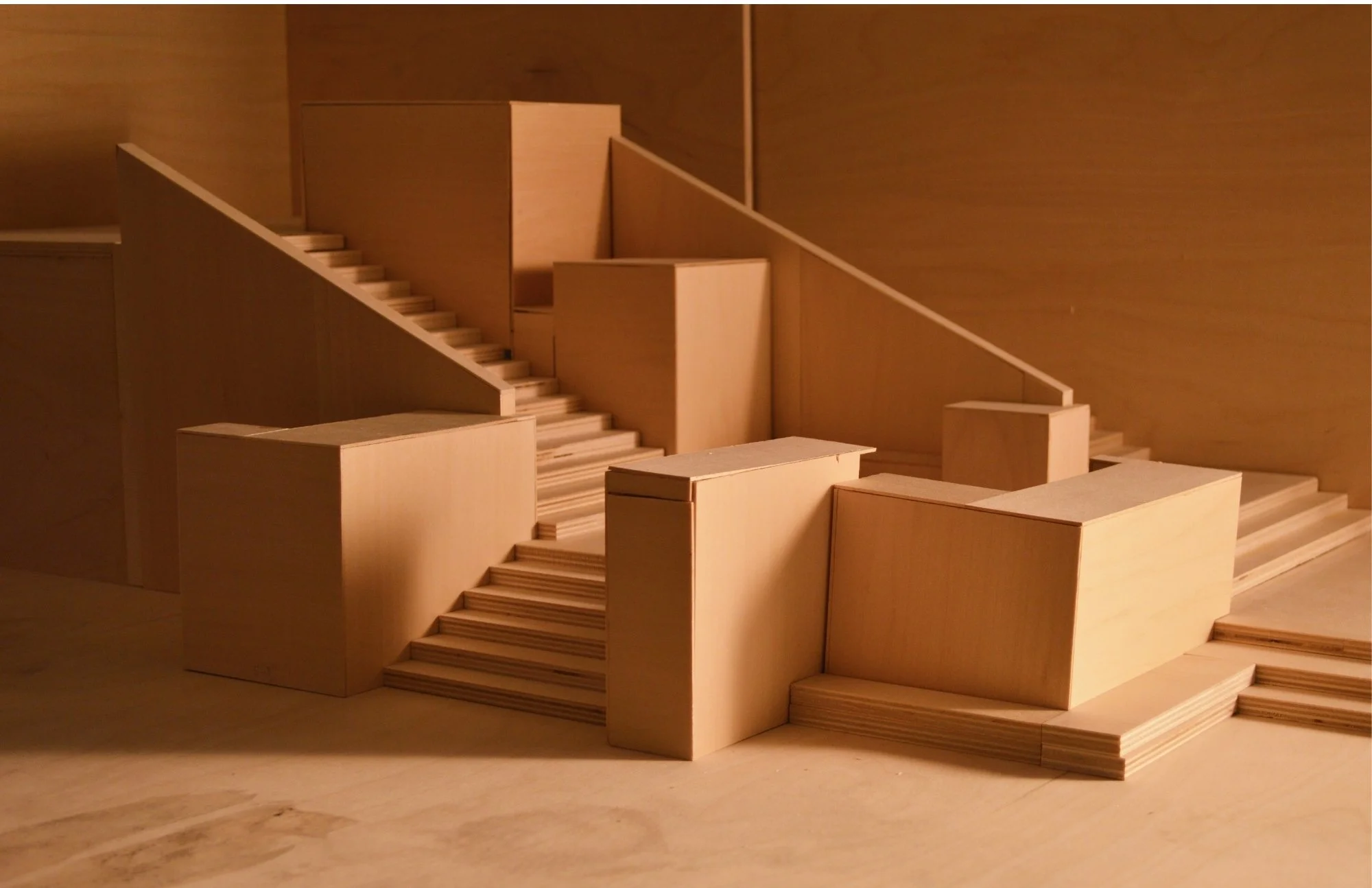A detailed wooden architectural model featuring multiple staircases, platforms, and walls, constructed from light-colored wood.