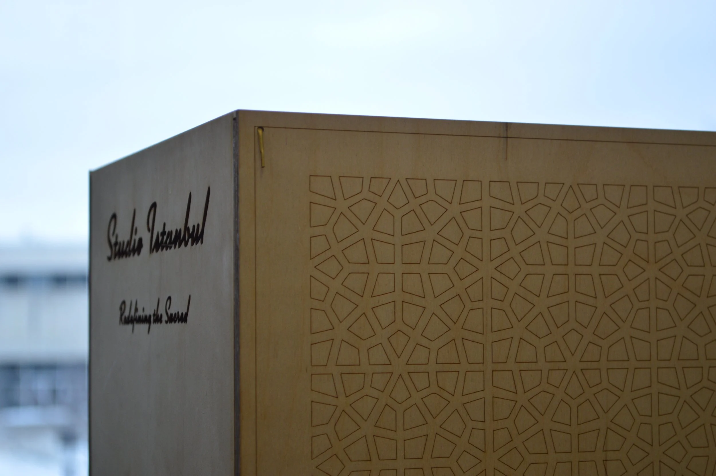 A wooden box with laser-cut geometric patterns and the partially visible text 'Studio Tembour' on the side.