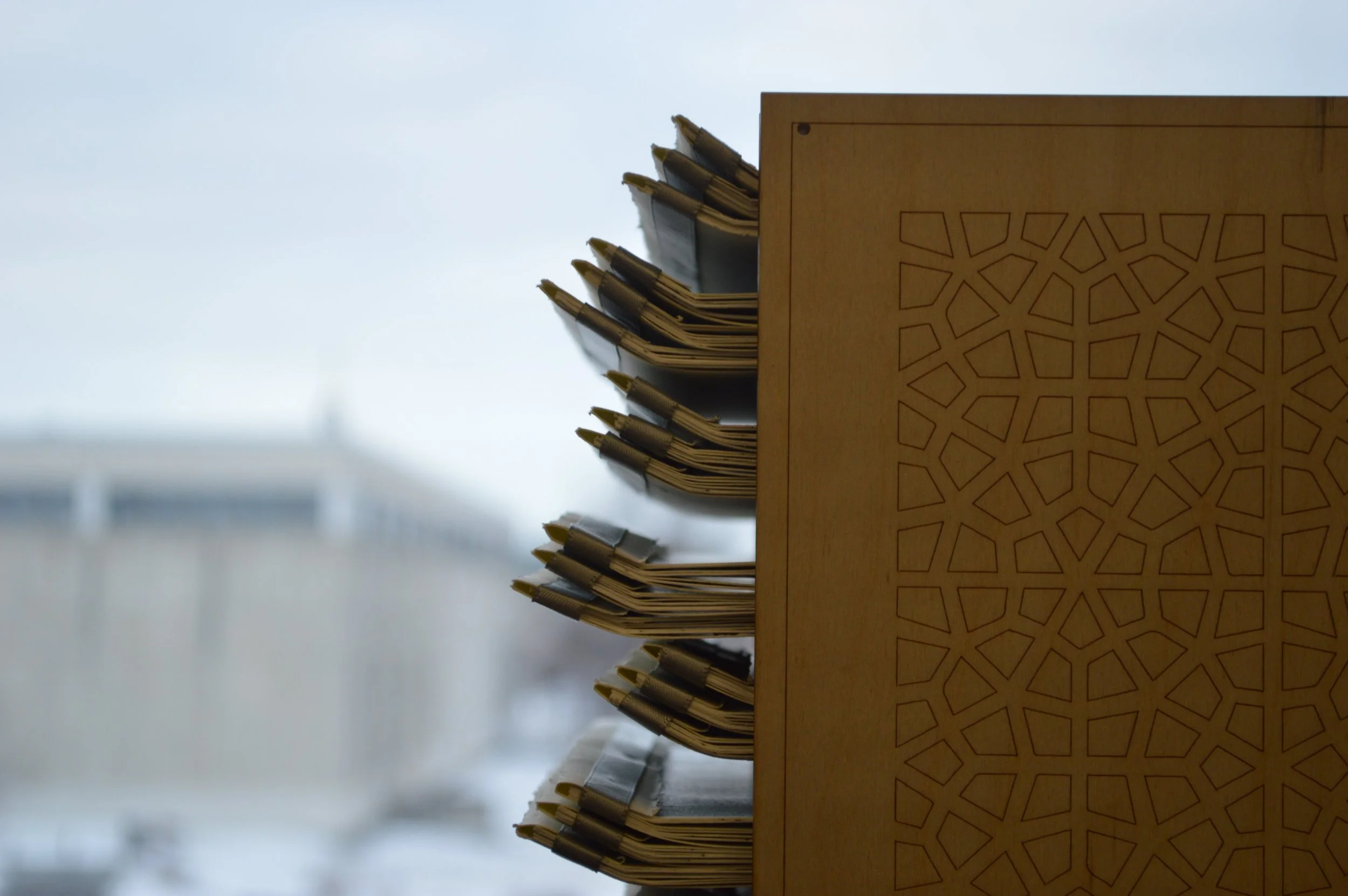 A wooden desk with a decorative pattern on its side. Several pens and folders are visible on top of the desk, arranged vertically along the edge.