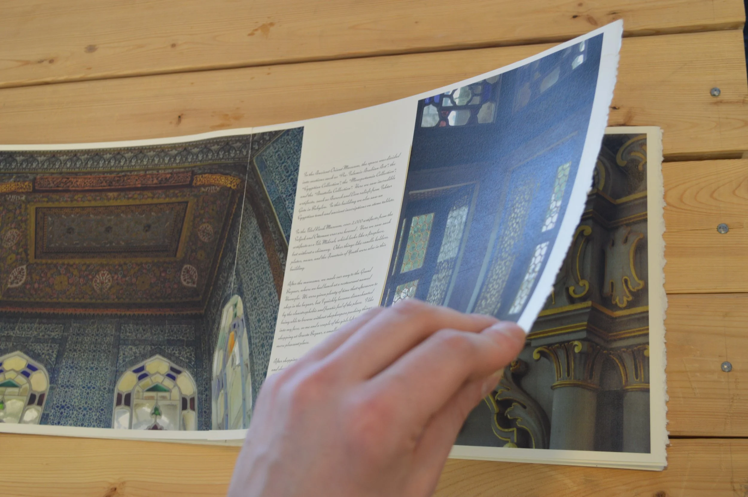 Person flipping through a brochure or magazine with images of ornate interior architecture.