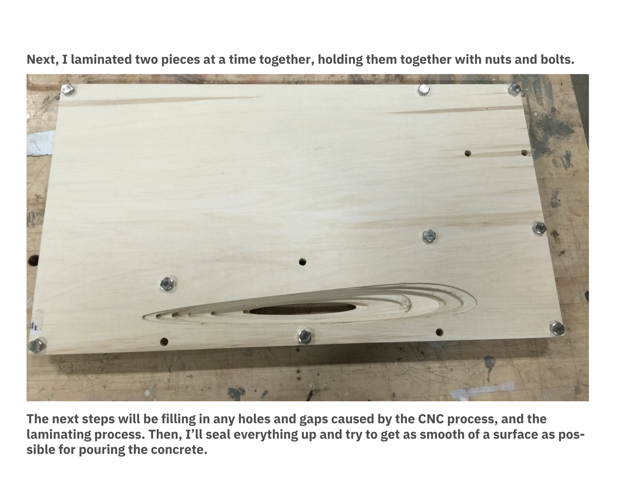 A wooden piece with six metal bolts on the corners and one in the center, placed on a workbench with visible marks and stains.