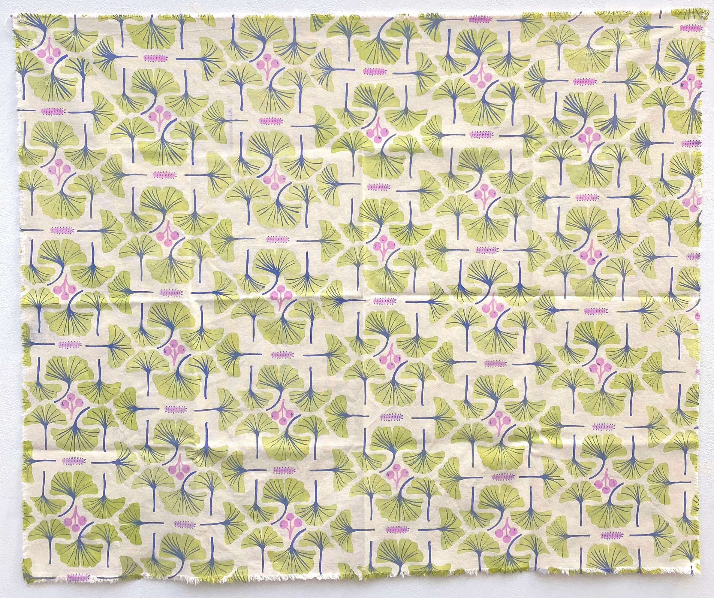 A piece of fabric with a repeating pattern of green ginkgo leaves and pink stylized flowers, accented with purple lines on a white background.