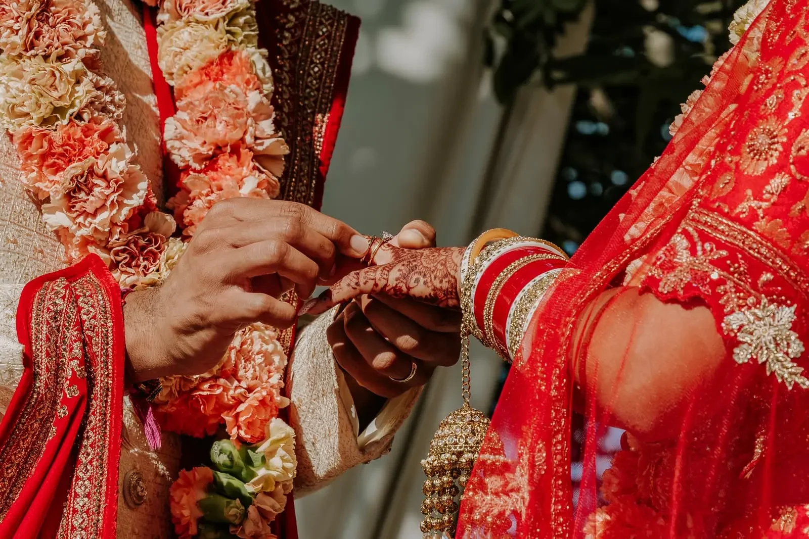 Close-up of a traditional Hindu wedding ring exchange during a luxury destination wedding in Sicily, Italy, showcasing mehndi, bridal jewelry, and colorful ceremonial attire.