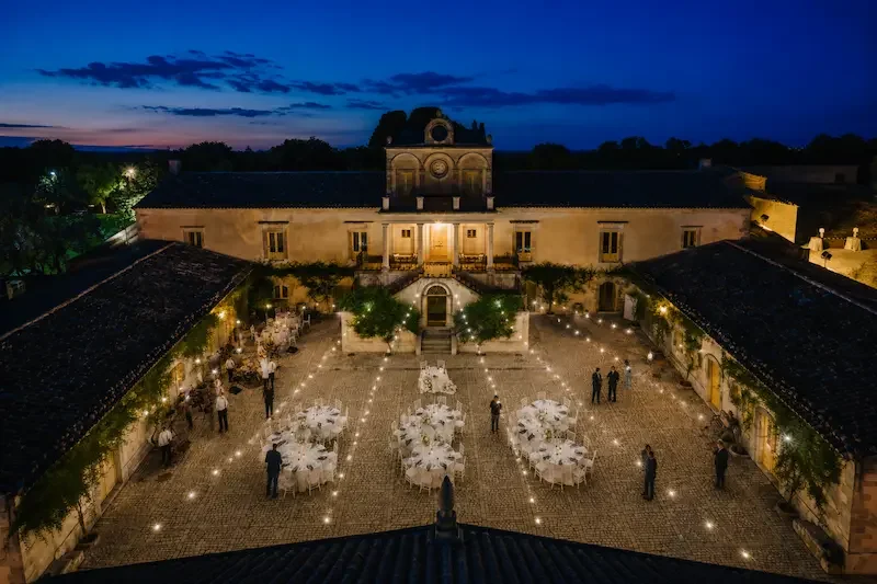 Drone view of Villa Fegotto at sunset in Sicily, luxury destination wedding venue in Ragusa with illuminated courtyard and elegant outdoor reception setup