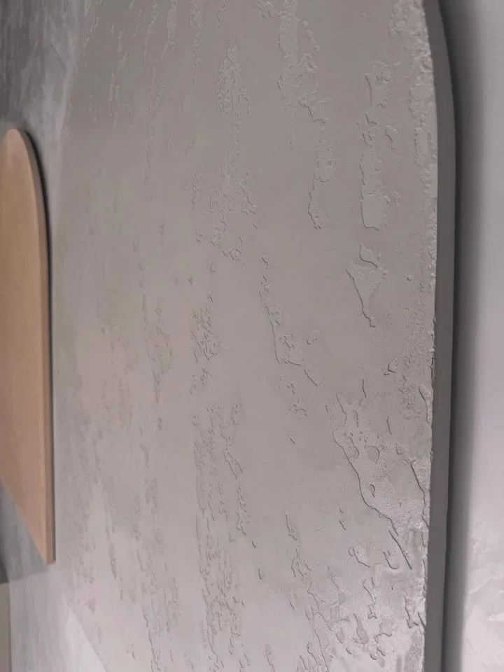 Close-up of a textured gray wall with a curved corner, showing paint peeling and cracking. russian stamp venetian plaster mornington peninsula showroom
