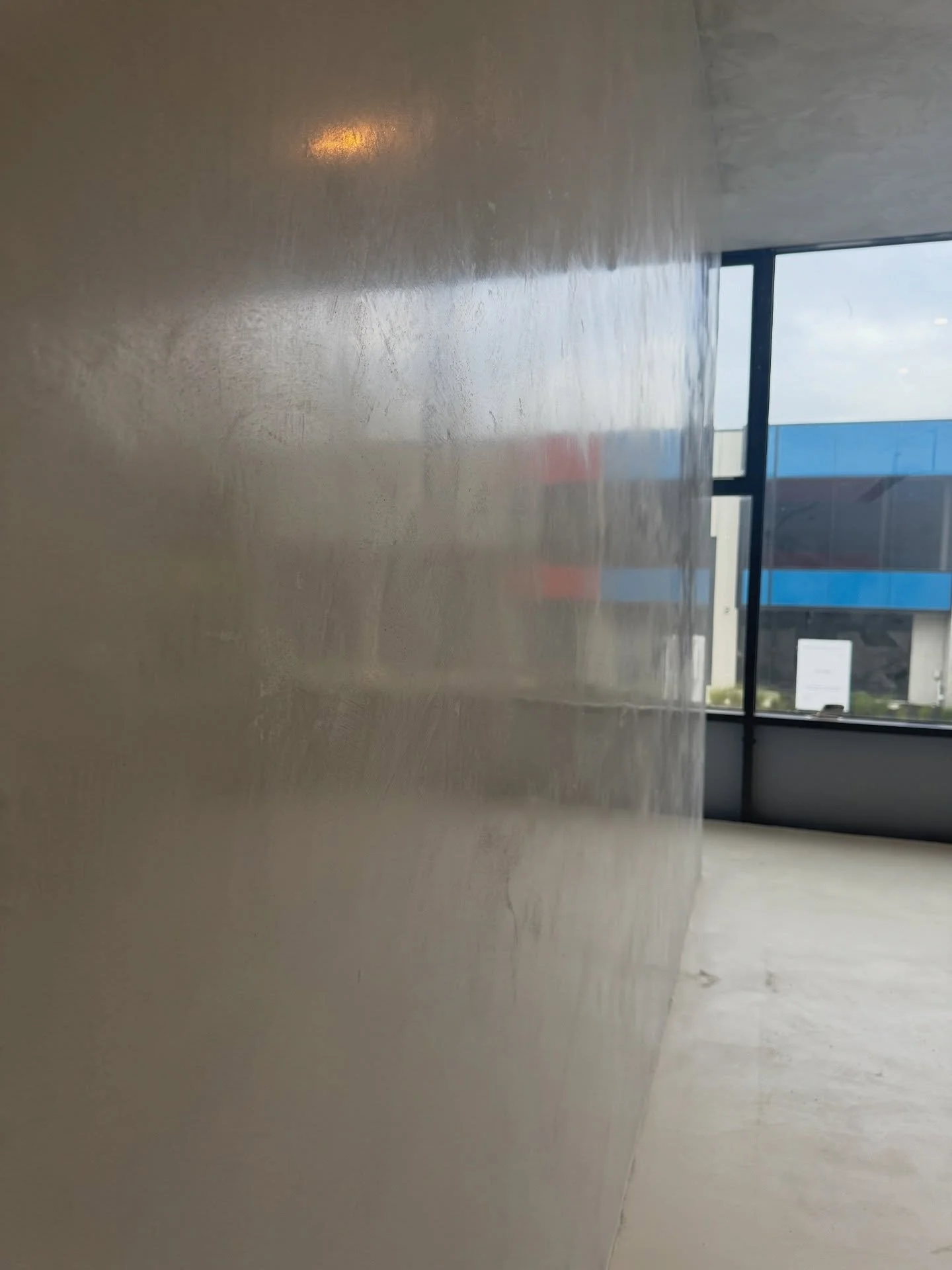 Interior view of an empty room with a large window showing a blue building outside, and a polished concrete wall.
Marmarino Naturale Venetian Plaster finish Mornington Peninsula