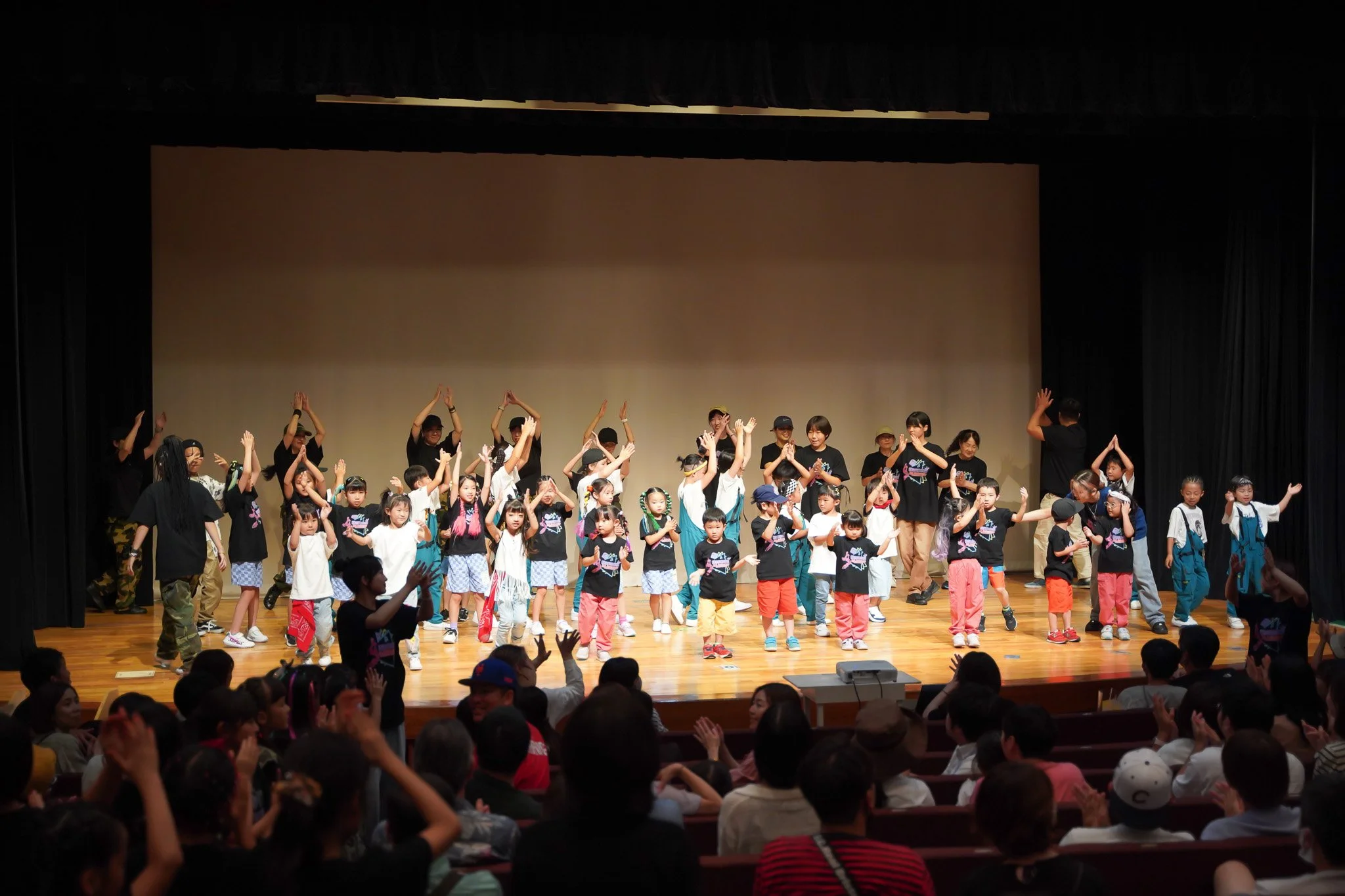 Children and adults on stage performing a dance or song during a school or community event in an auditorium.