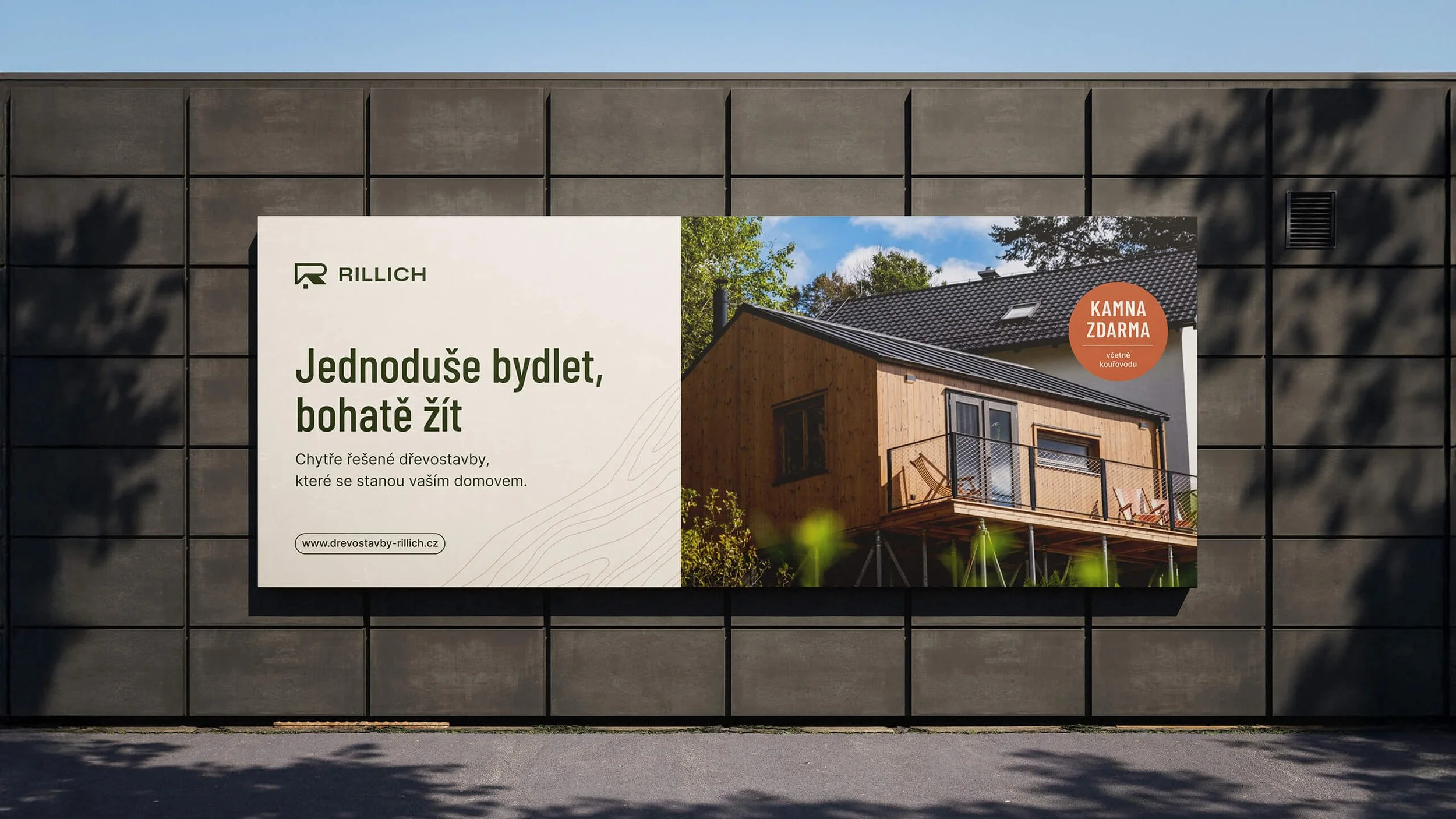 Venkovní billboard značky Rillich s nápisem a fotkou modulárního domu.
