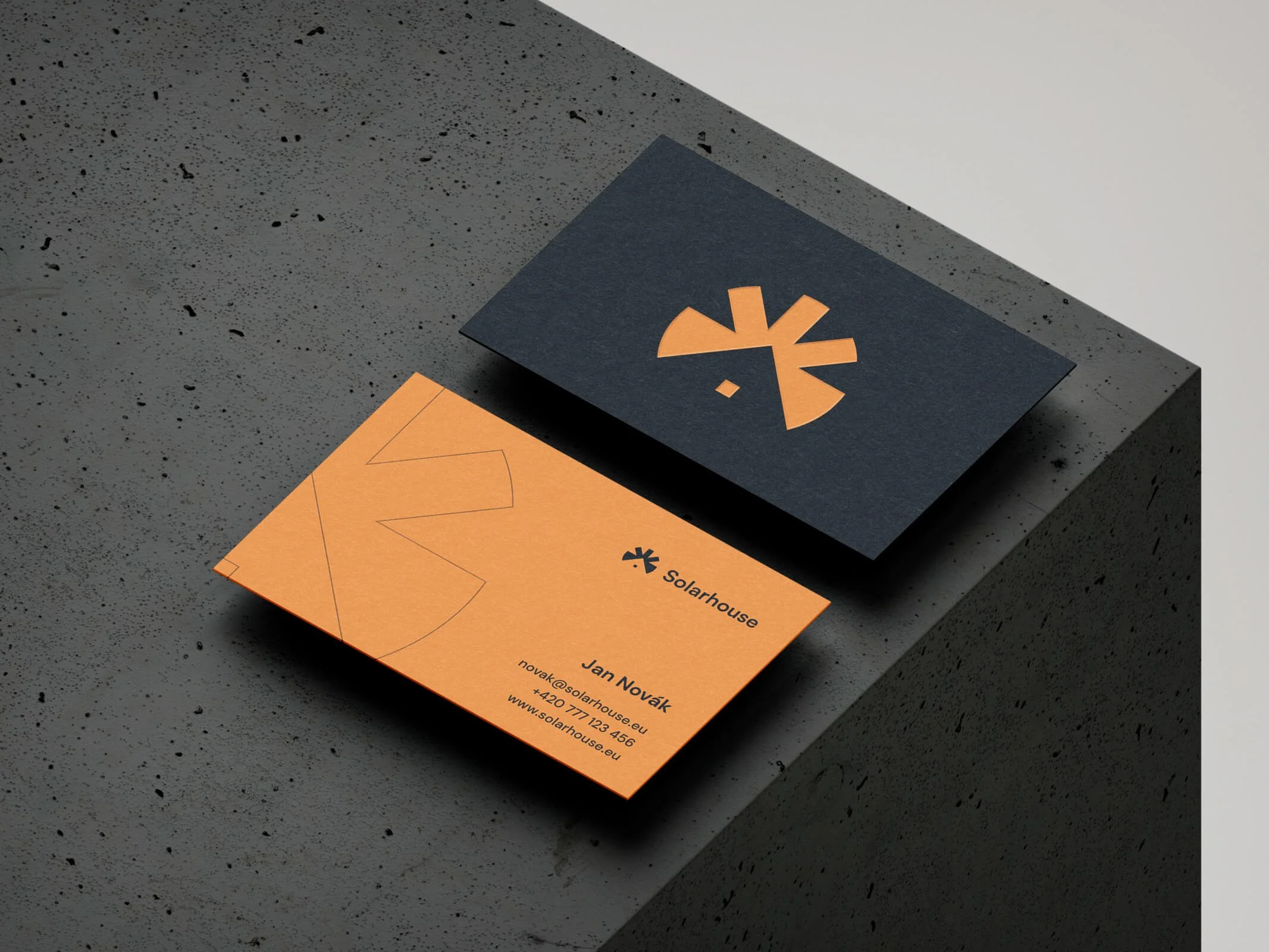 Vizitky značky Solarhouse levitující na betonovém povrchu.