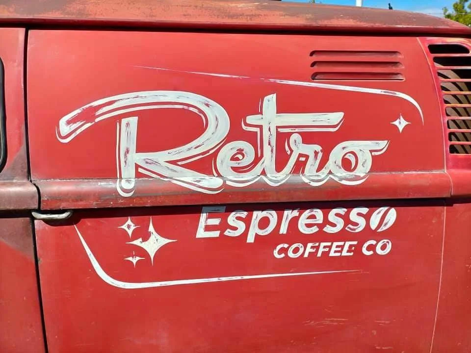 Vintage red vehicle with white lettering that reads 'Retro Espresso Coffee Co' in a retro style, with decorative sparkles.
