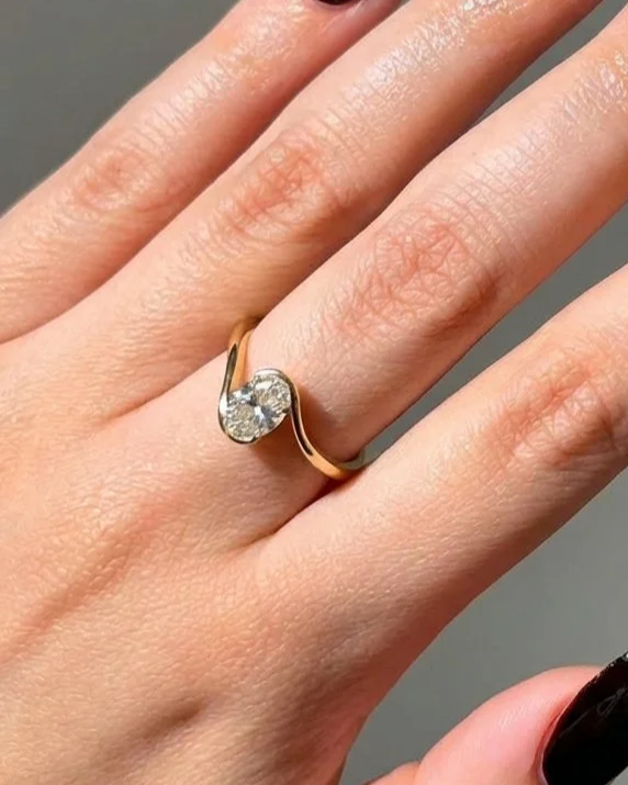 Close-up of a hand with a gold ring featuring a single large diamond on the ring finger.