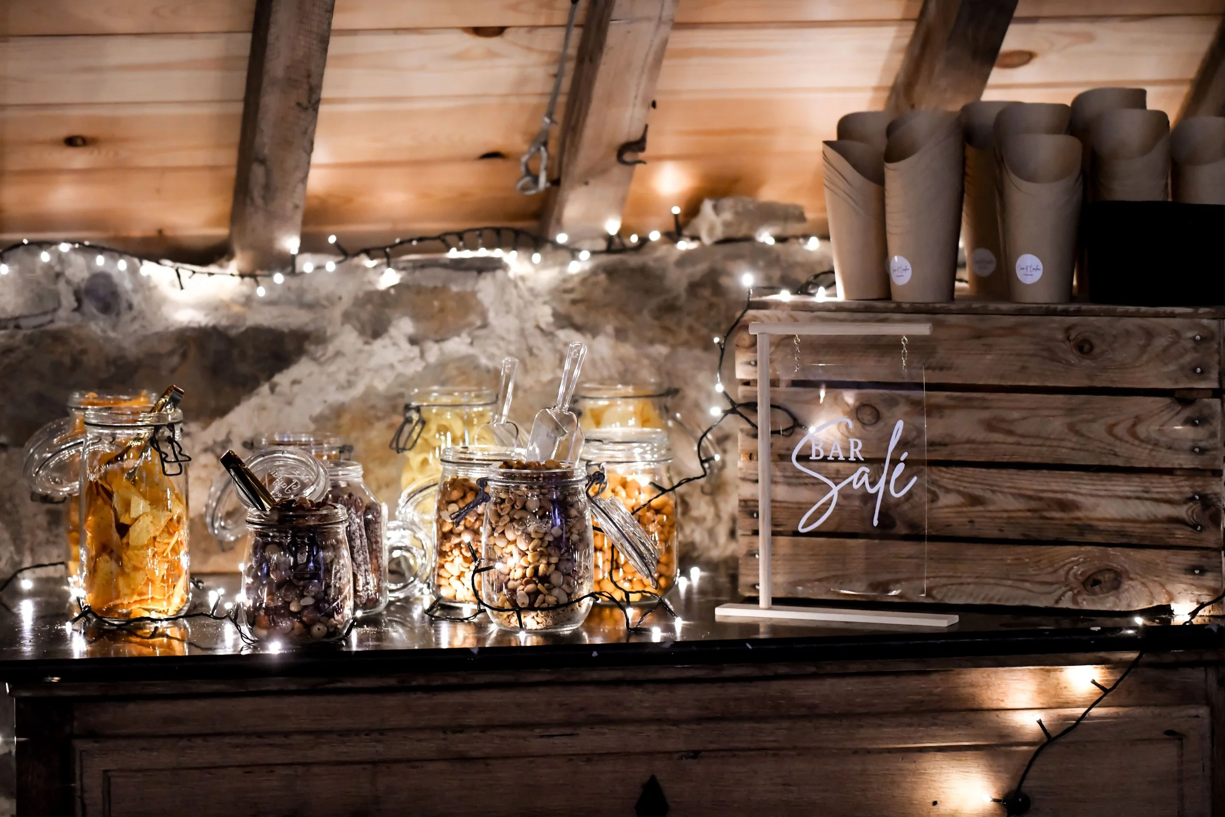 Un comptoir en bois avec plusieurs bocaux remplis de biscuits, décoré de guirlandes lumineuses, avec un panneau indiquant « Bar Salé ».