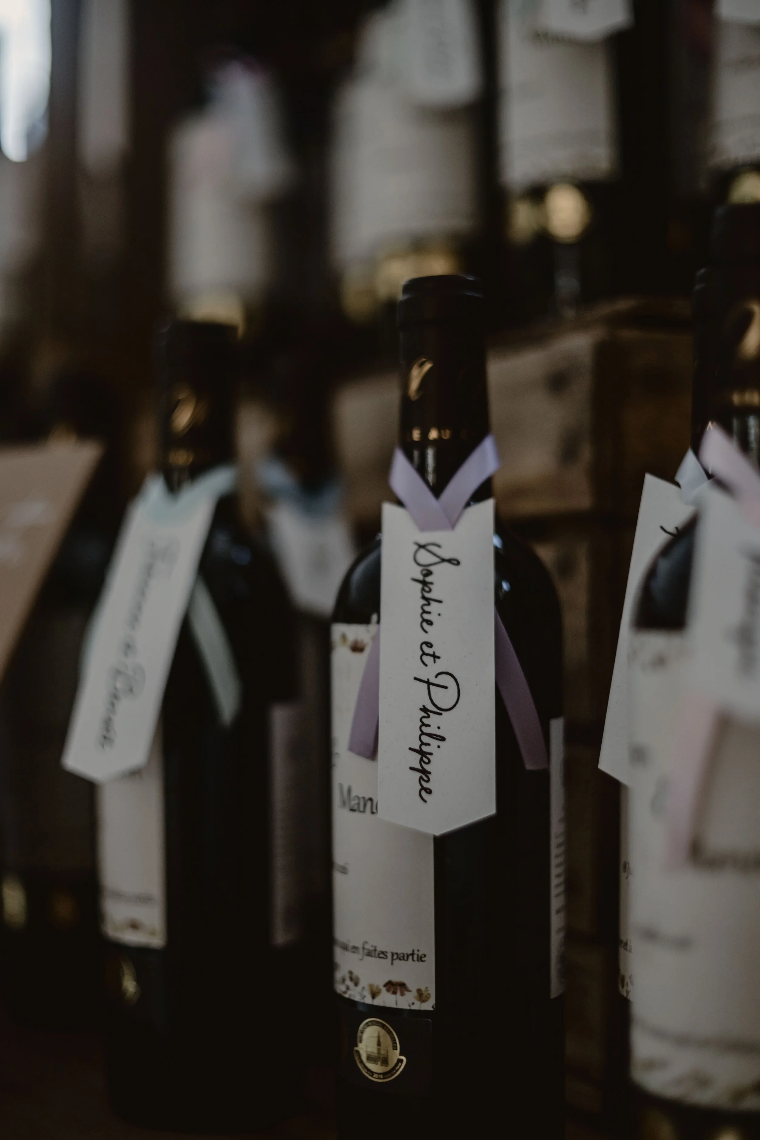 Des bouteilles de vin avec des étiquettes en papier attachées autour du goulot, exposées en rangée.