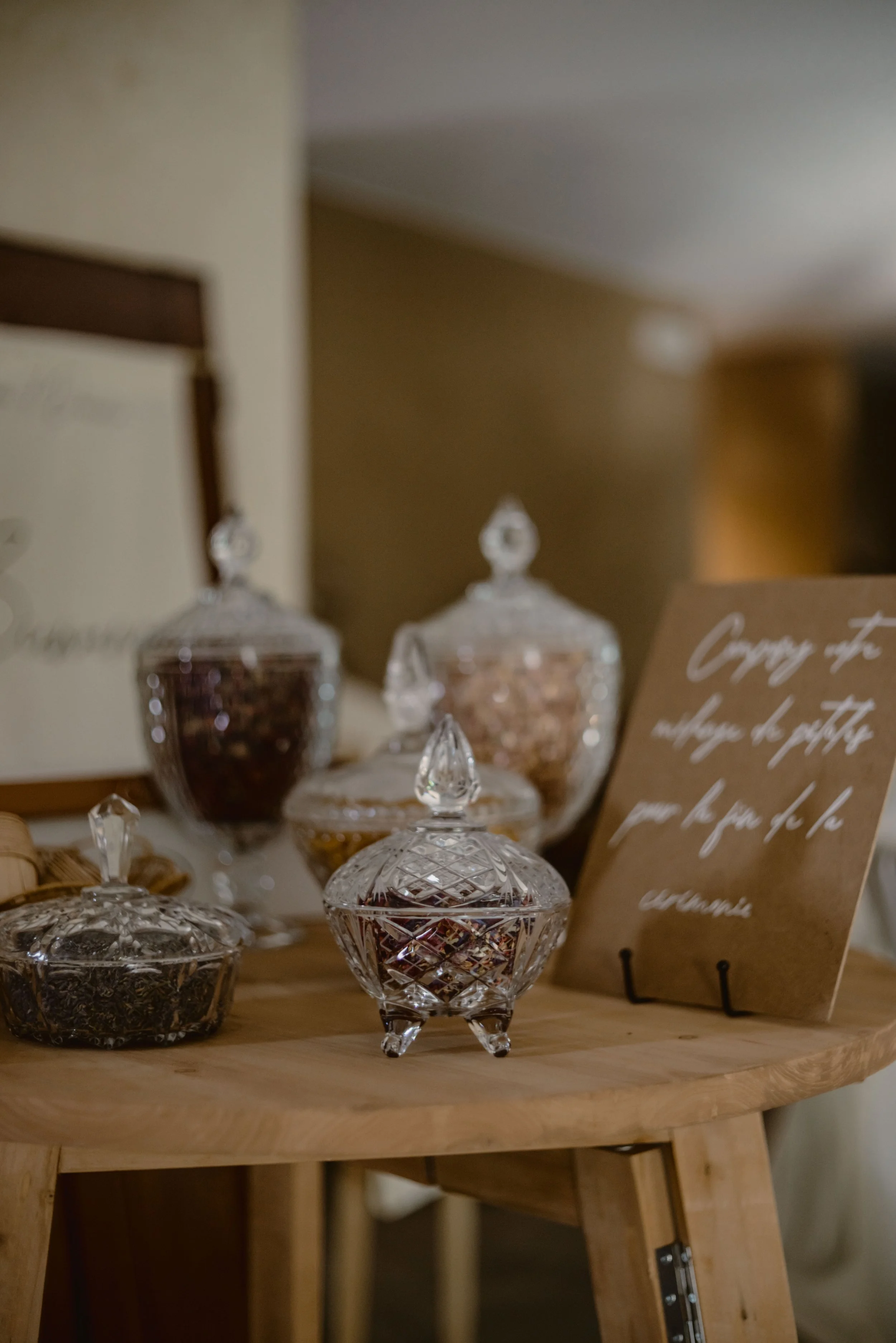 Vitrine avec plusieurs bocaux en verre contenant des bonbons ou des décorations en verre, sur une étagère en bois.