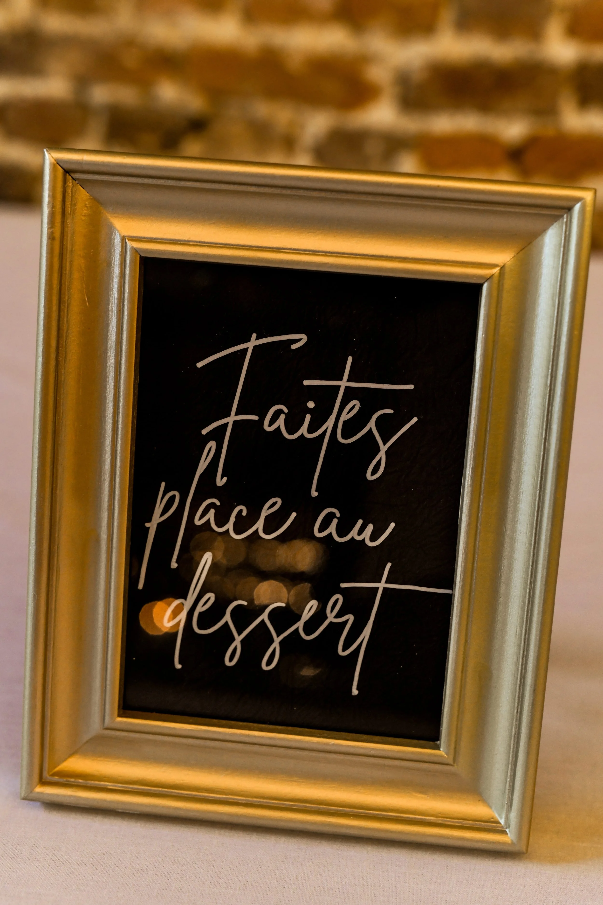 Un cadre doré contenant un tableau noir avec une écriture blanche manuscrite indiquant "Faites place au dessert".