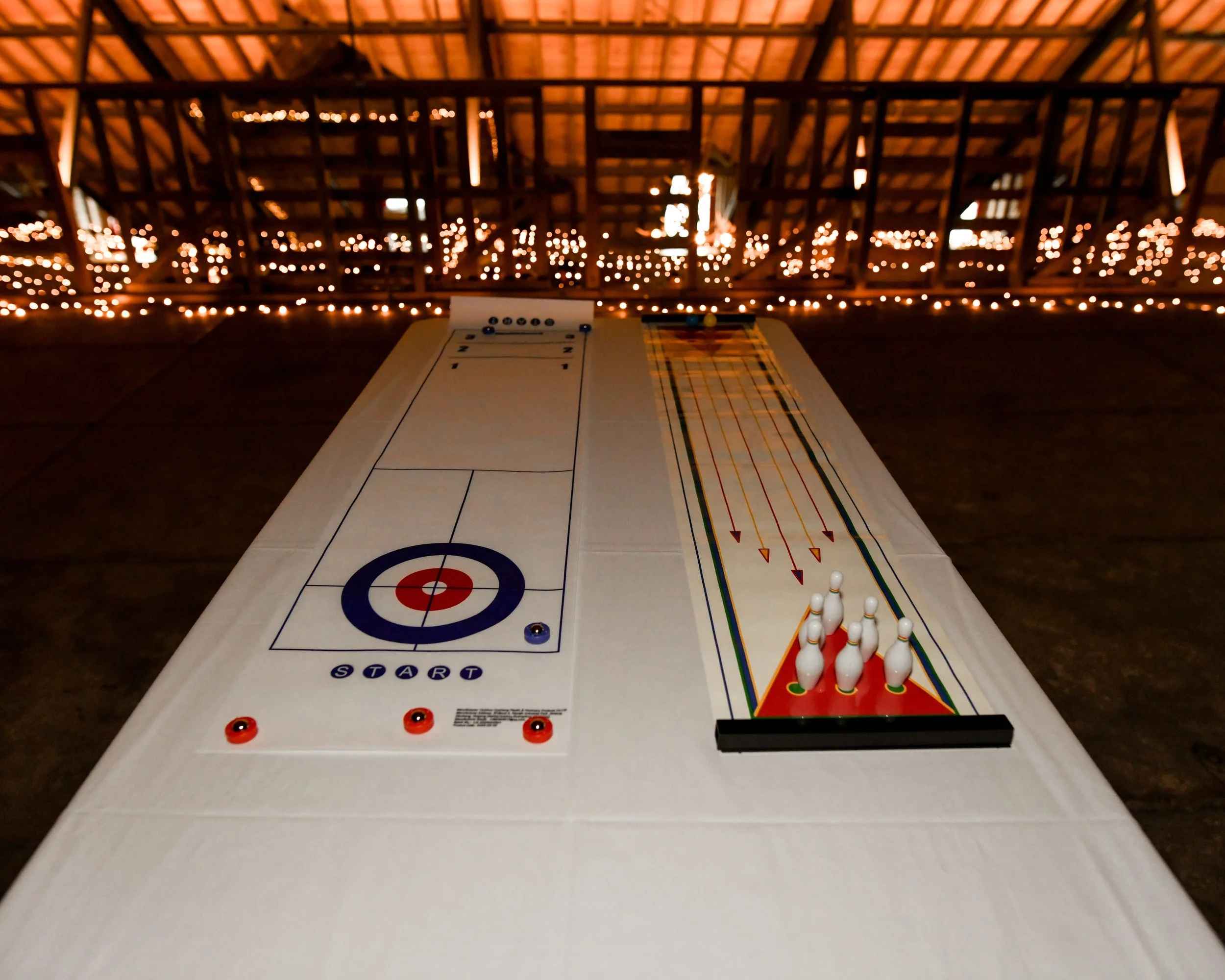 Jeu de hockey de table et jeu de palets sur une table en bois dans un espace éclairé par des guirlandes lumineuses, dans un environnement intérieur avec toit en bois.