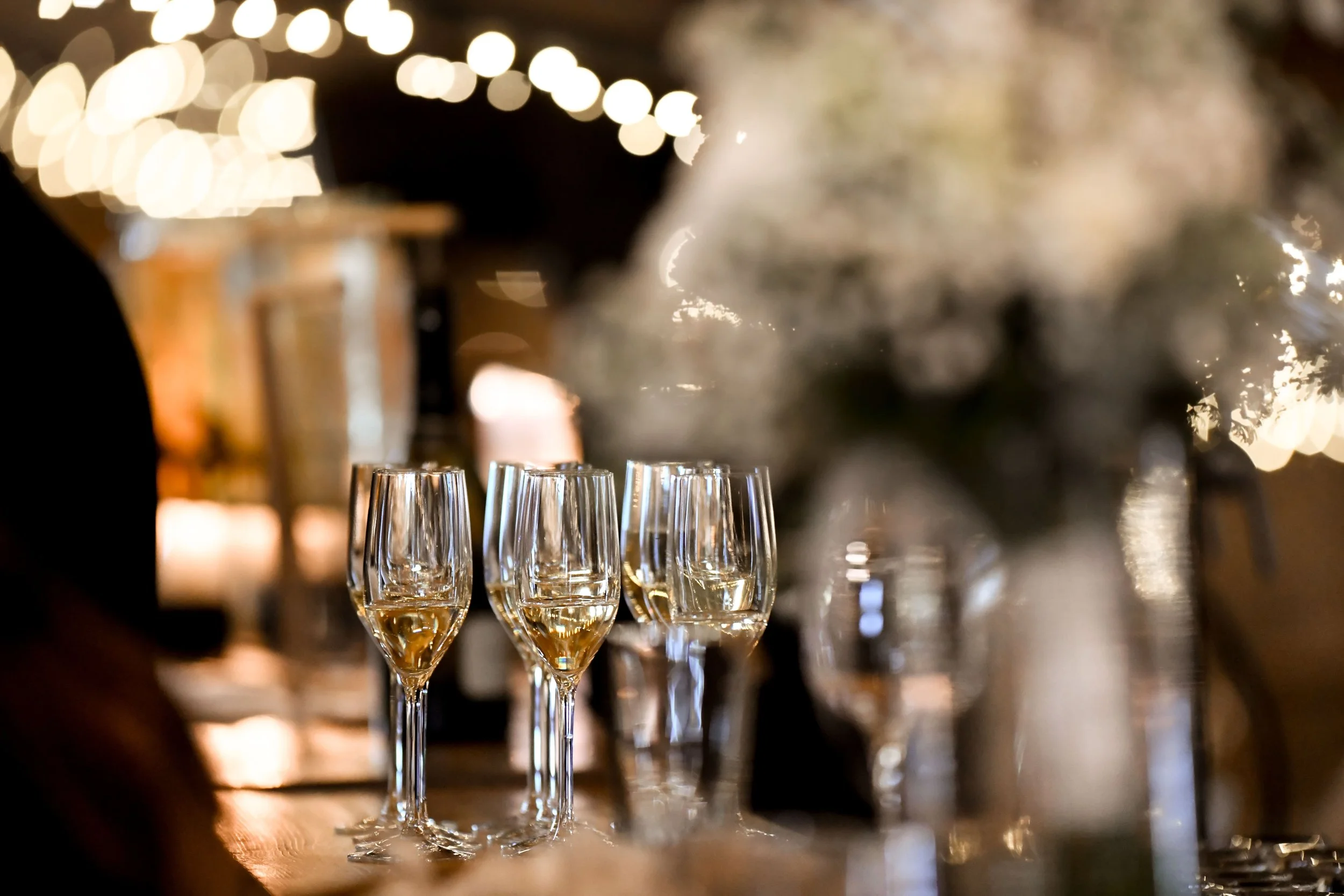 Verres de champagne alignés sur un bar lors d'une célébration dans une ambiance chaleureuse et festive.
