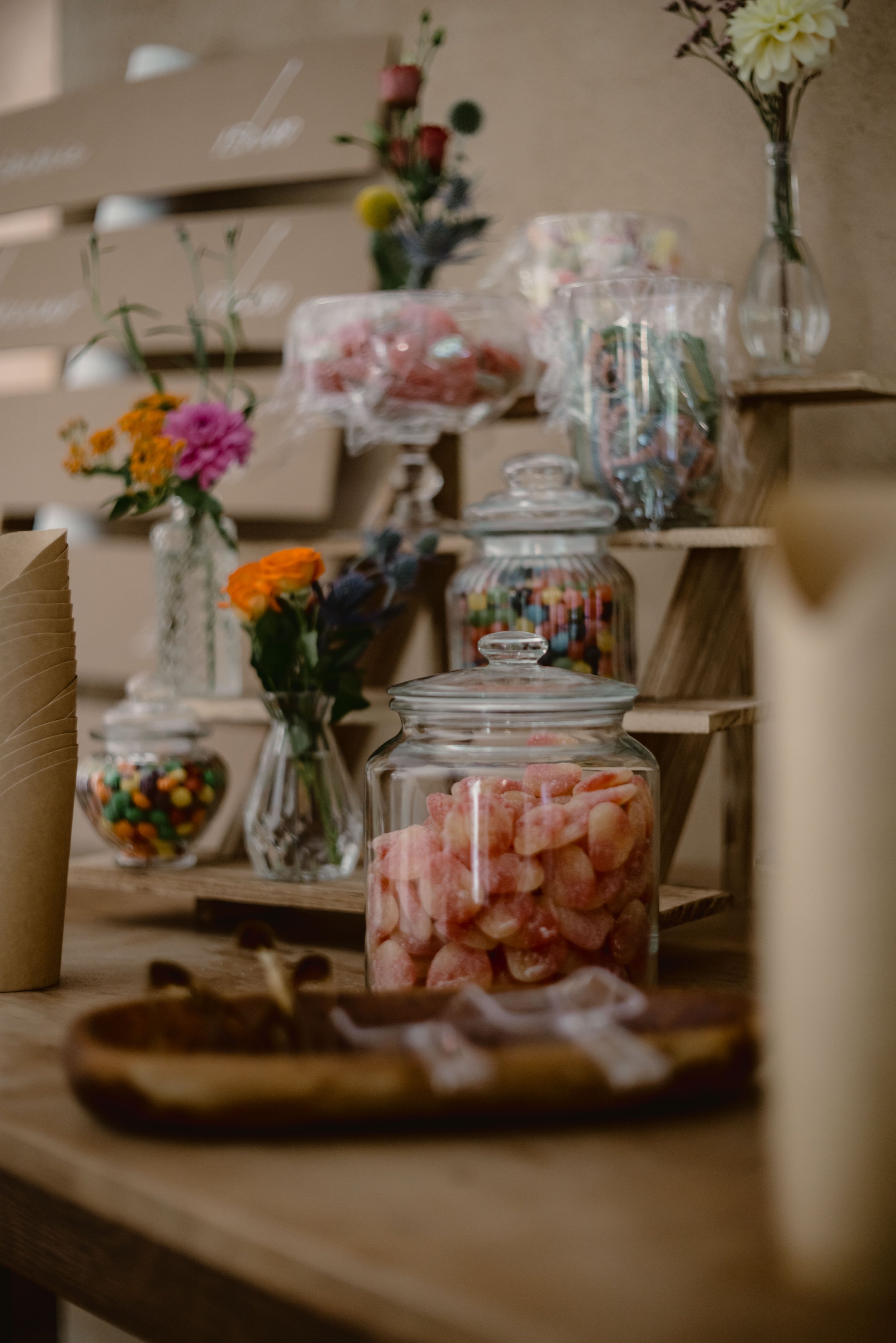 Gâteaux et bonbons dans des bocaux en verre, fleurs colorées dans des vases, décorations pour une fête ou un événement. Faible mise au point.