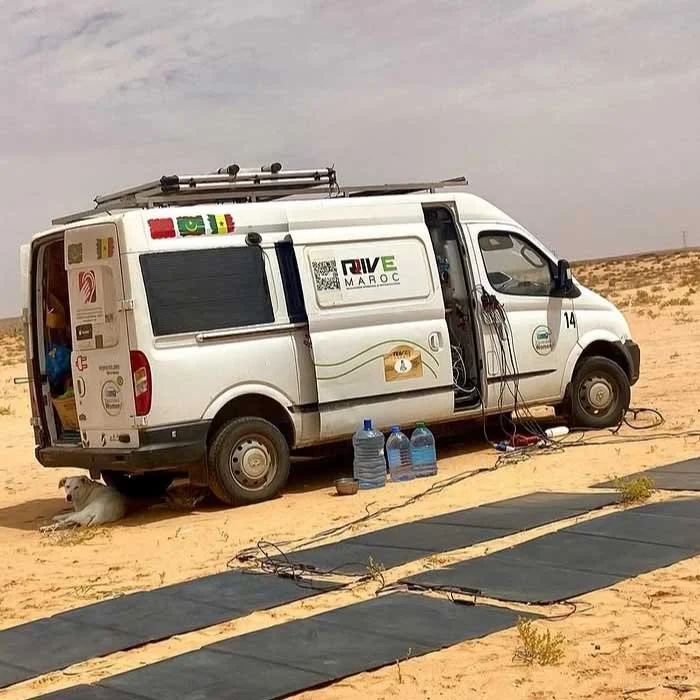 Mobiles Bürofahrzeug im Wüstengebiet mit Wasserbehältern, Solarmatten und Ausrüstung für eine Funkübertragung.