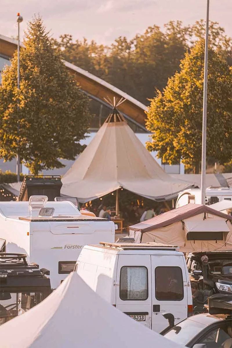 Campingplatz mit Zelten, Campern und Bäumen bei Sonnenuntergang.