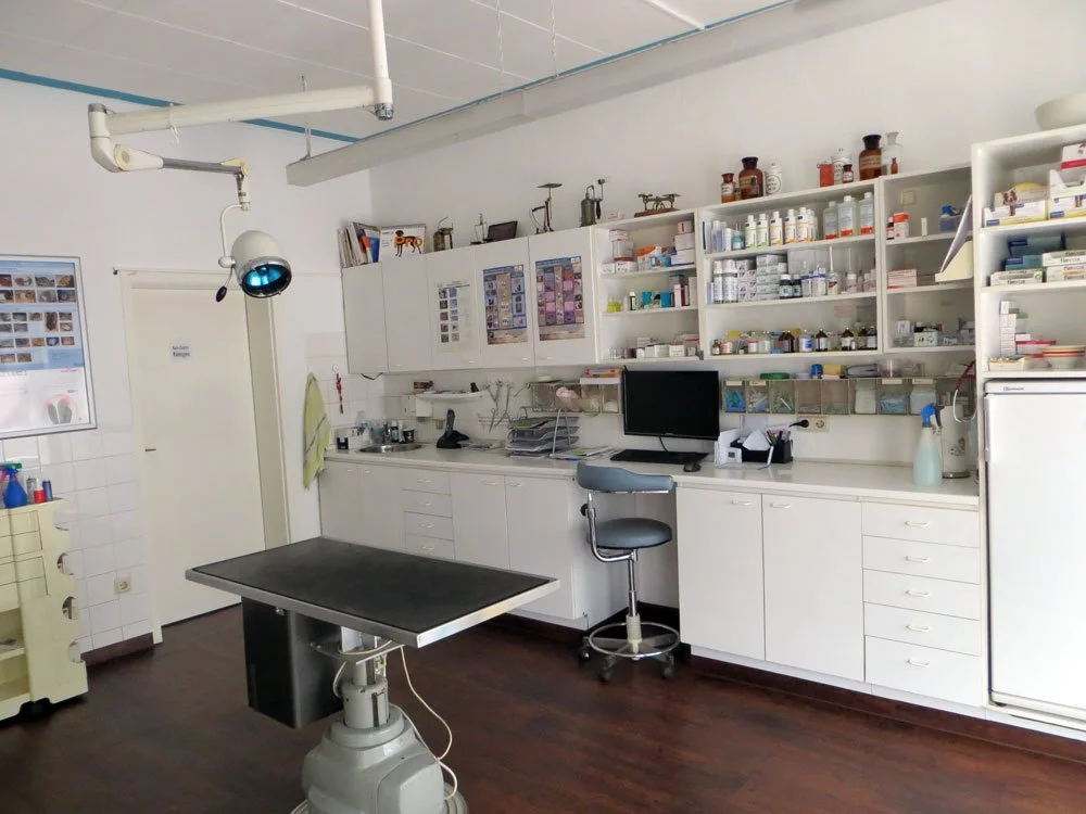 Arztpraxis mit medizinischen Geräten, Schränken voller Medikamenten und Monitoren.